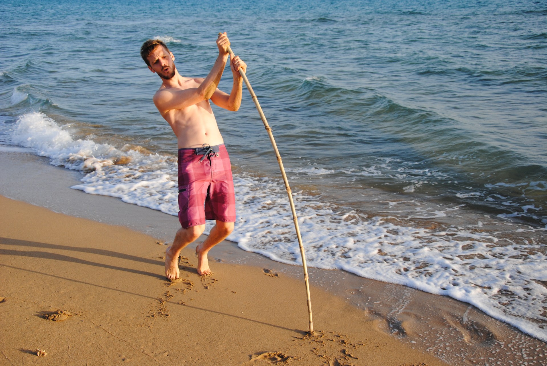 Sebastian steckt einen langen Stock in den Strand