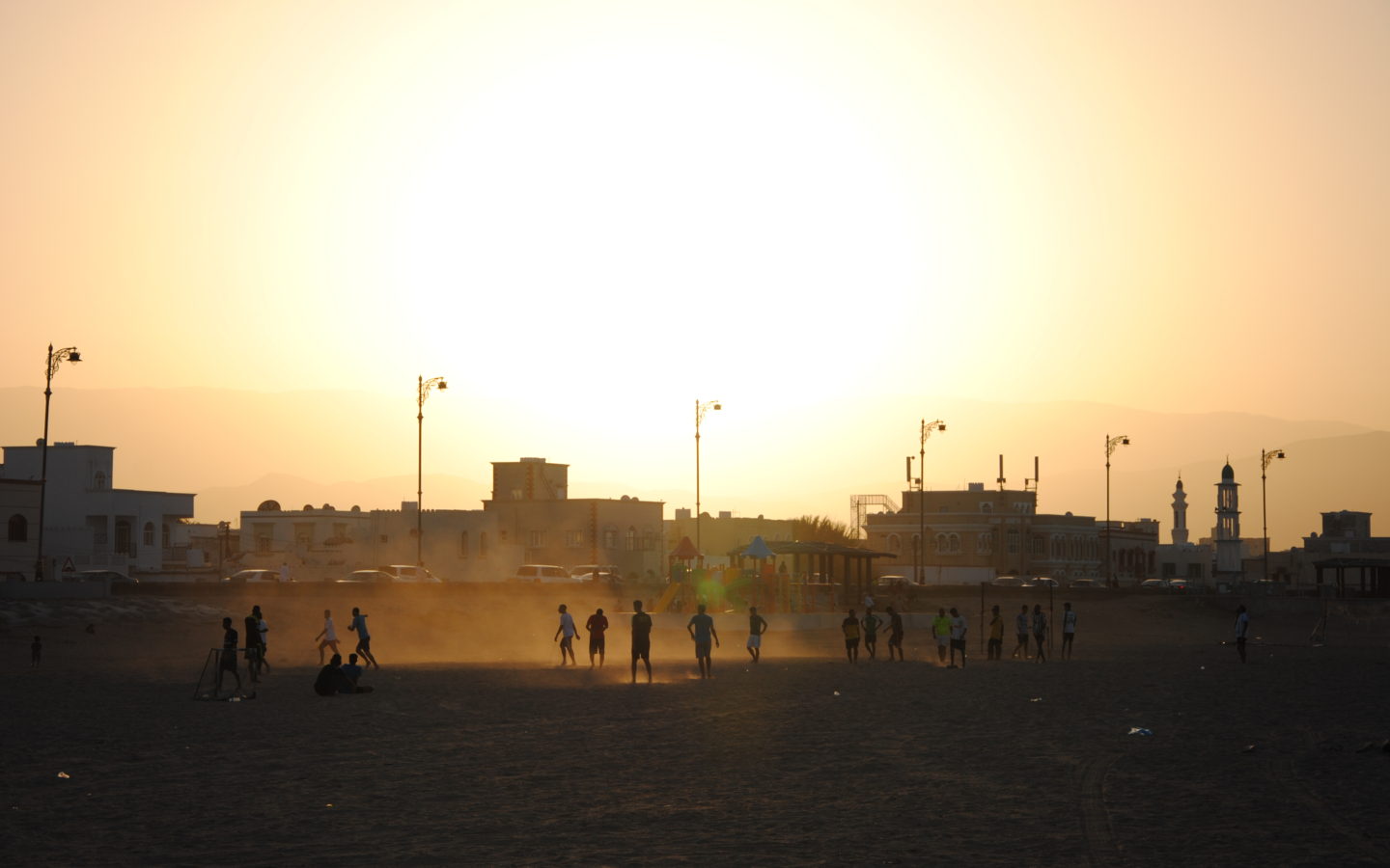 Menschen spielen im Abendlicht Fußball am Strand