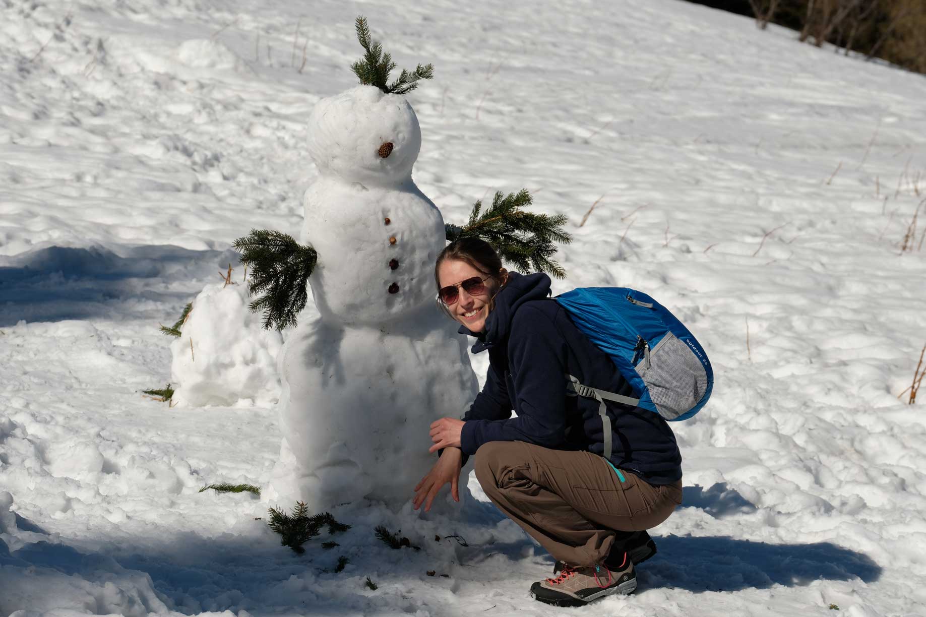 Leo in der Hocke vor einem Schneemann