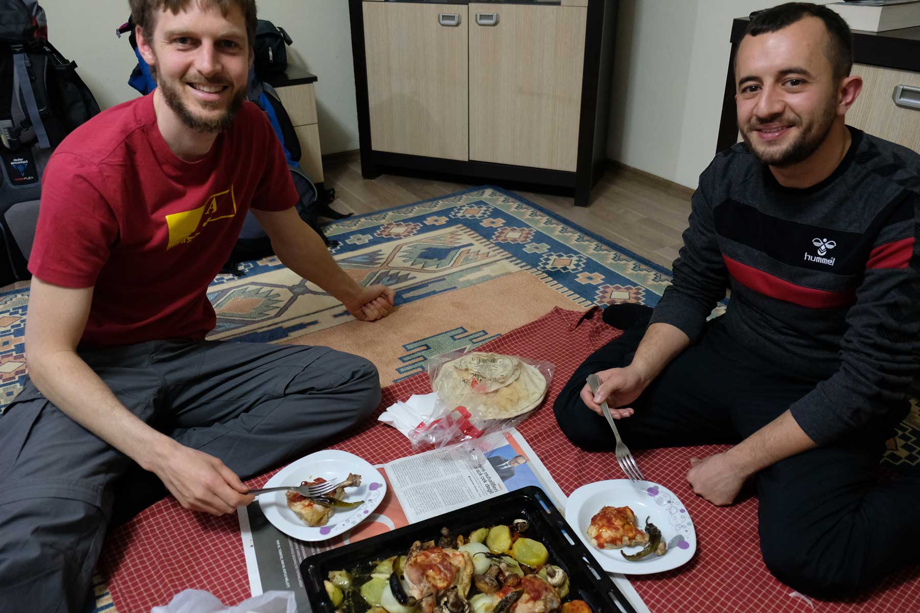 Sebastian und Fatih sitzen auf dem Boden und essen