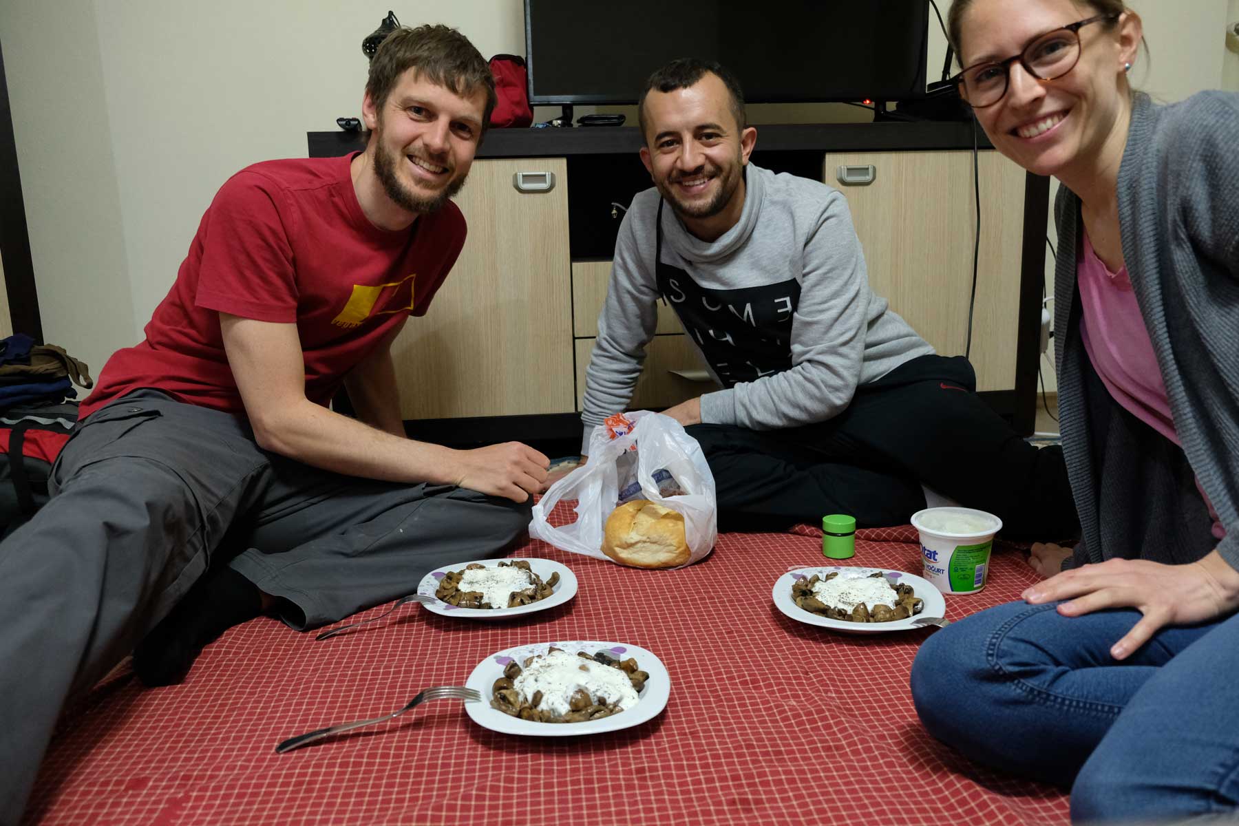 Sebastian und Leo sitzen mit Fatih auf dem Boden und essen