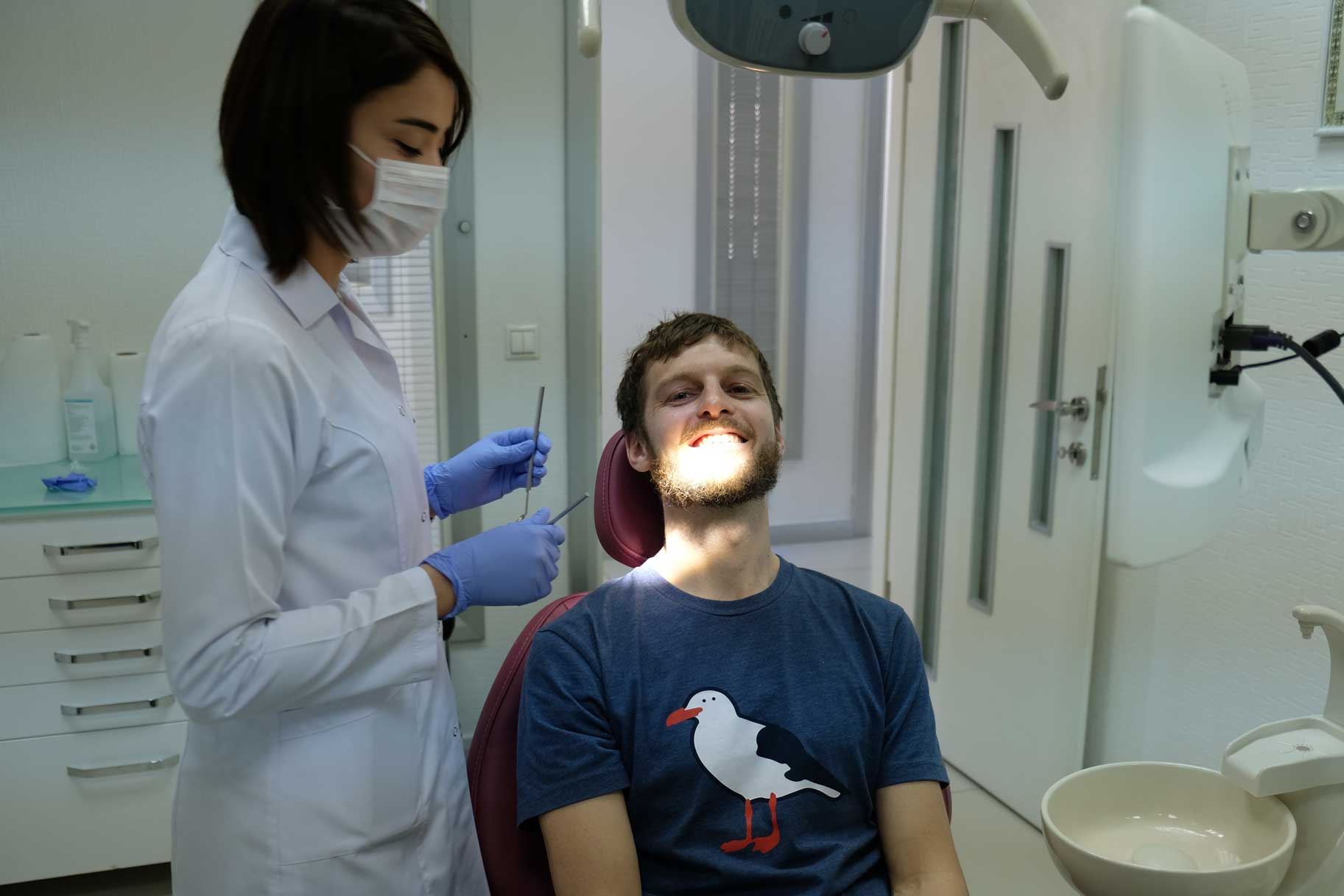 Sebastian sitzt auf einem Zahnarztstuhl. Neben ihm steht eine Arzthelferin.
