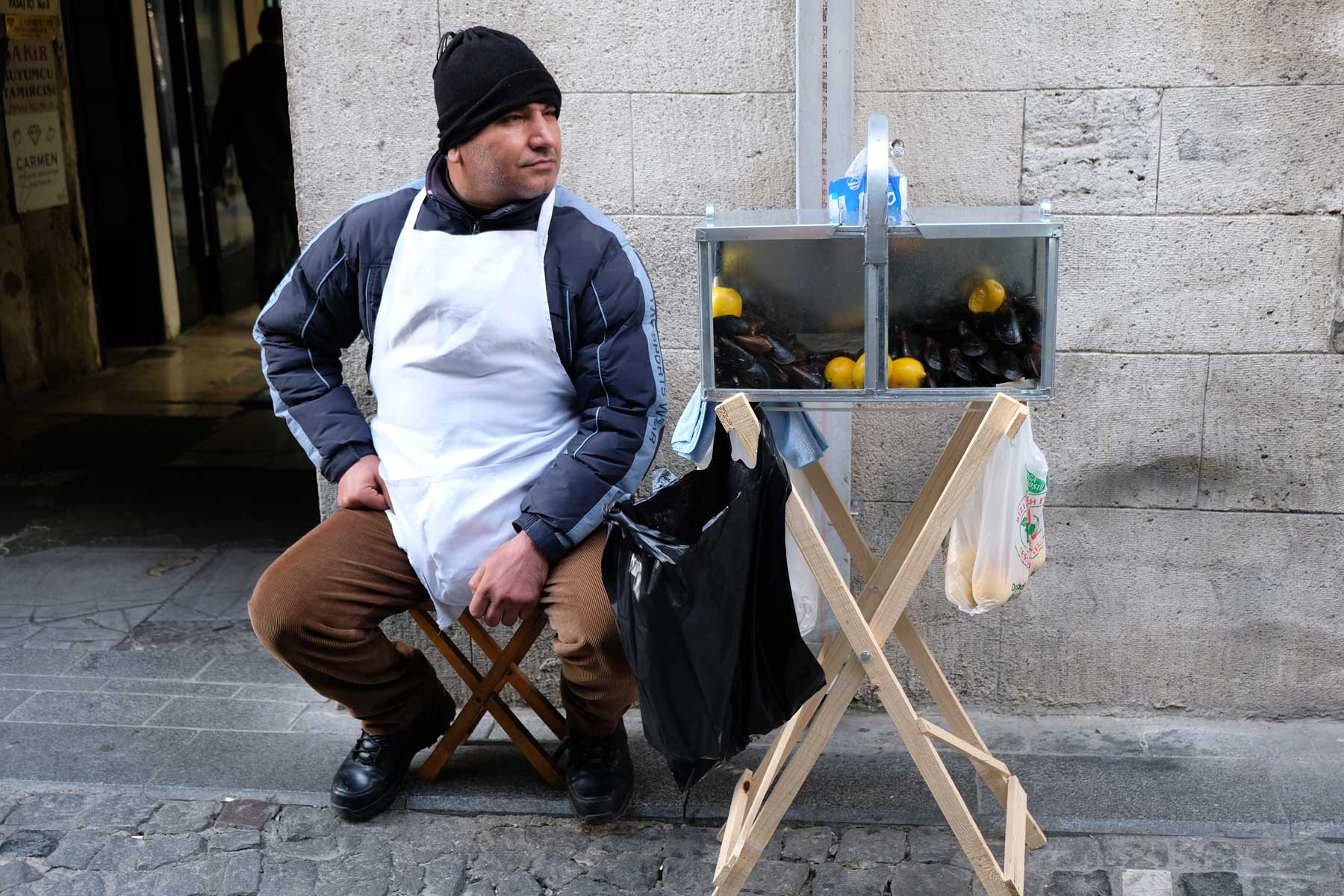 Ein Verkäufer sitzt neben einer Kiste mit Miesmuscheln