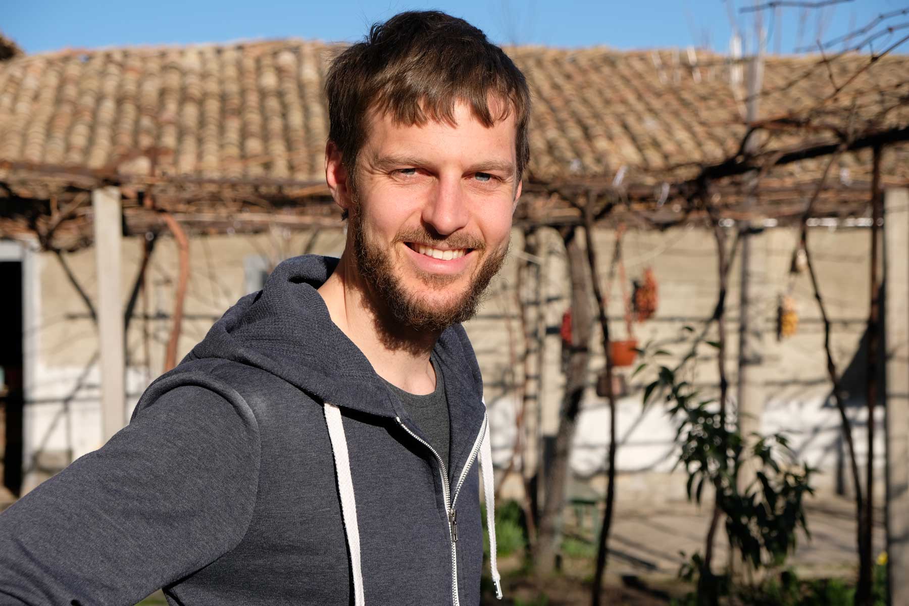 Sebastian steht in der Abendsonne vor einem Haus