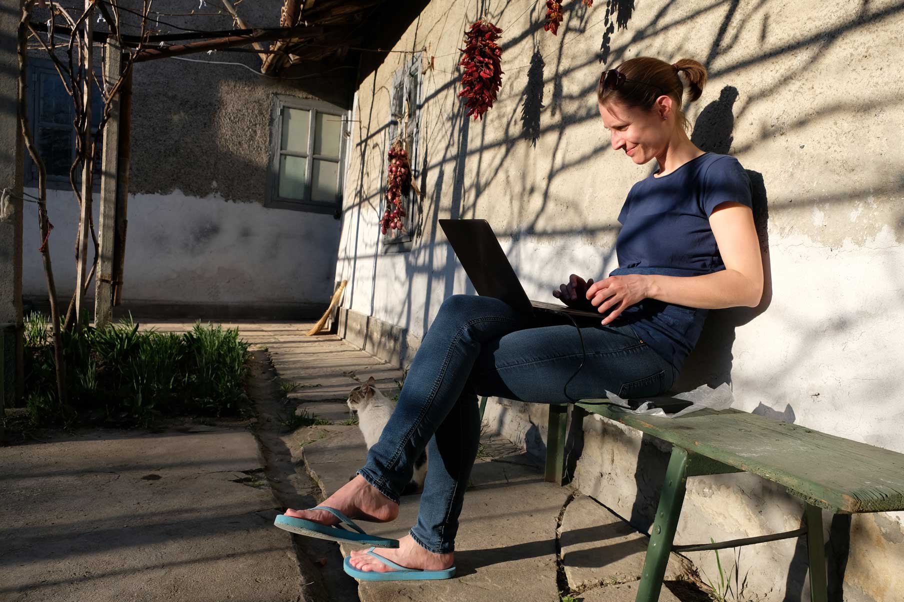 Leo sitz in der Sonne und schreibt auf ihrem Laptop