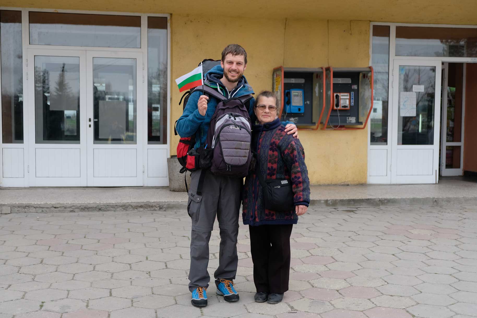 Sebastian steht mit Gepäck neben Petranka und hält eine Bulgarienfahne