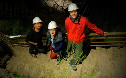 Mustafa, Natalia und Sebastian stehen auf einer Treppe. Alle tragen weiße Schutzhelme.