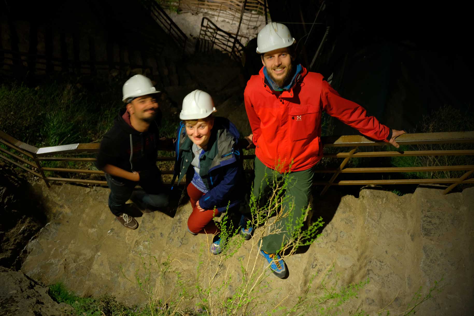 Mustafa, Natalia und Sebastian stehen auf einer Treppe. Alle tragen weiße Schutzhelme.