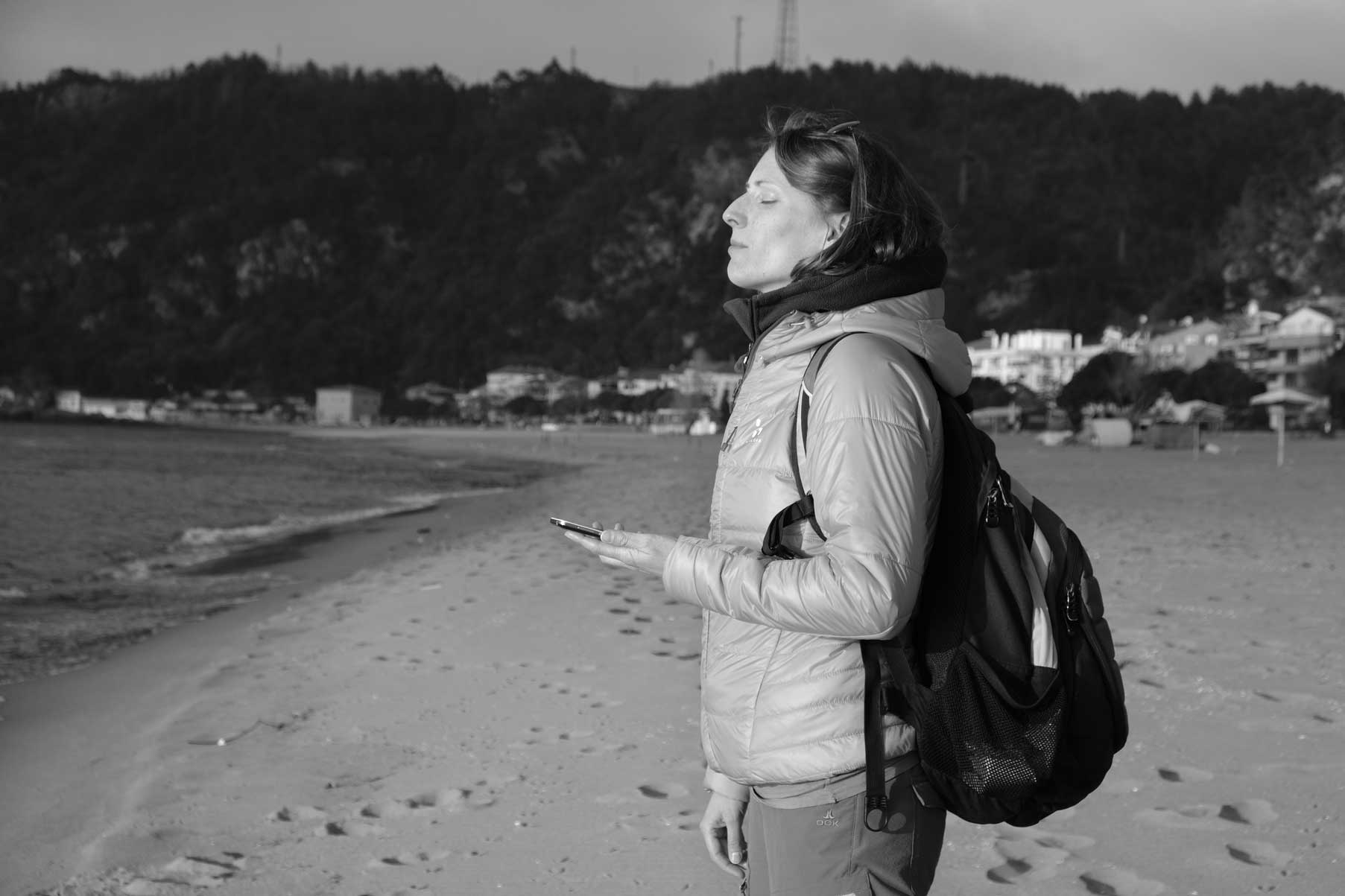 Leo steht mit Handy in der Hand am Strand