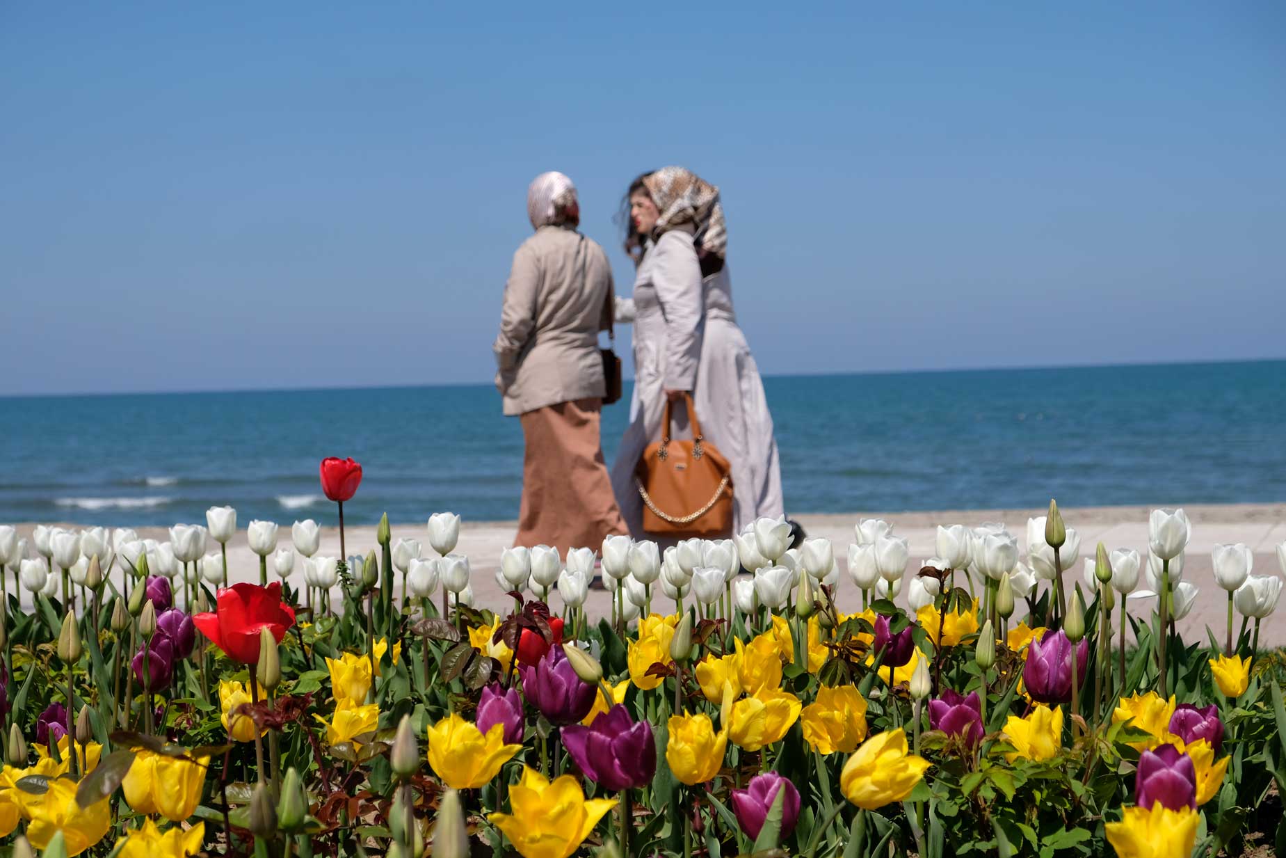 Türkische Frauen spazieren an der Uferpromenade vor einem Tulpenbeet