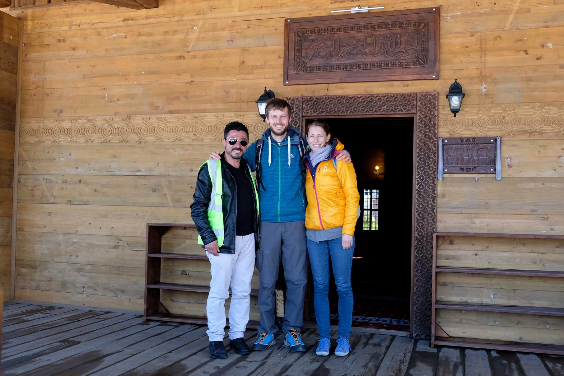 Sebastian und Leo stehen mit einem Mann vor der Holzmoschee