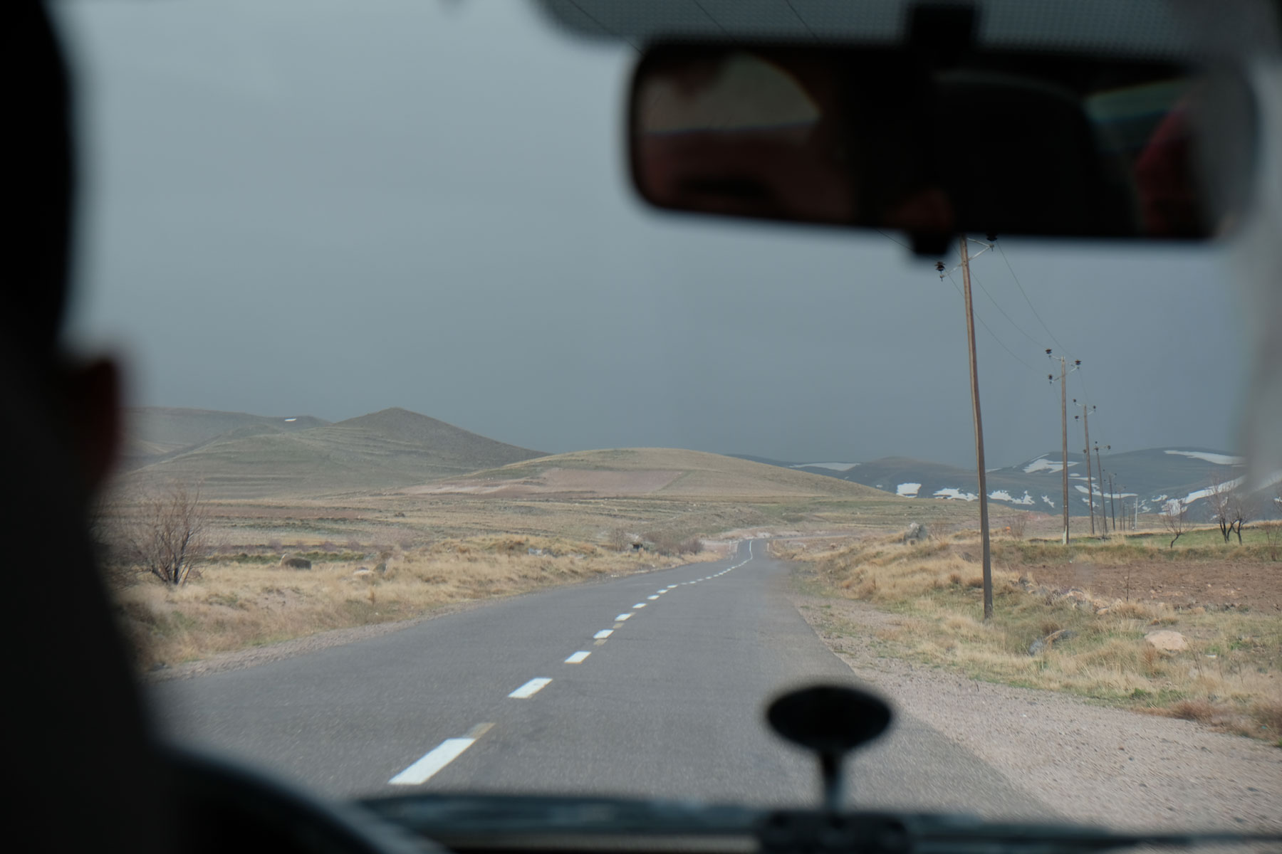 Blick aus dem Auto auf eine Straße und schwarze Regenwolken