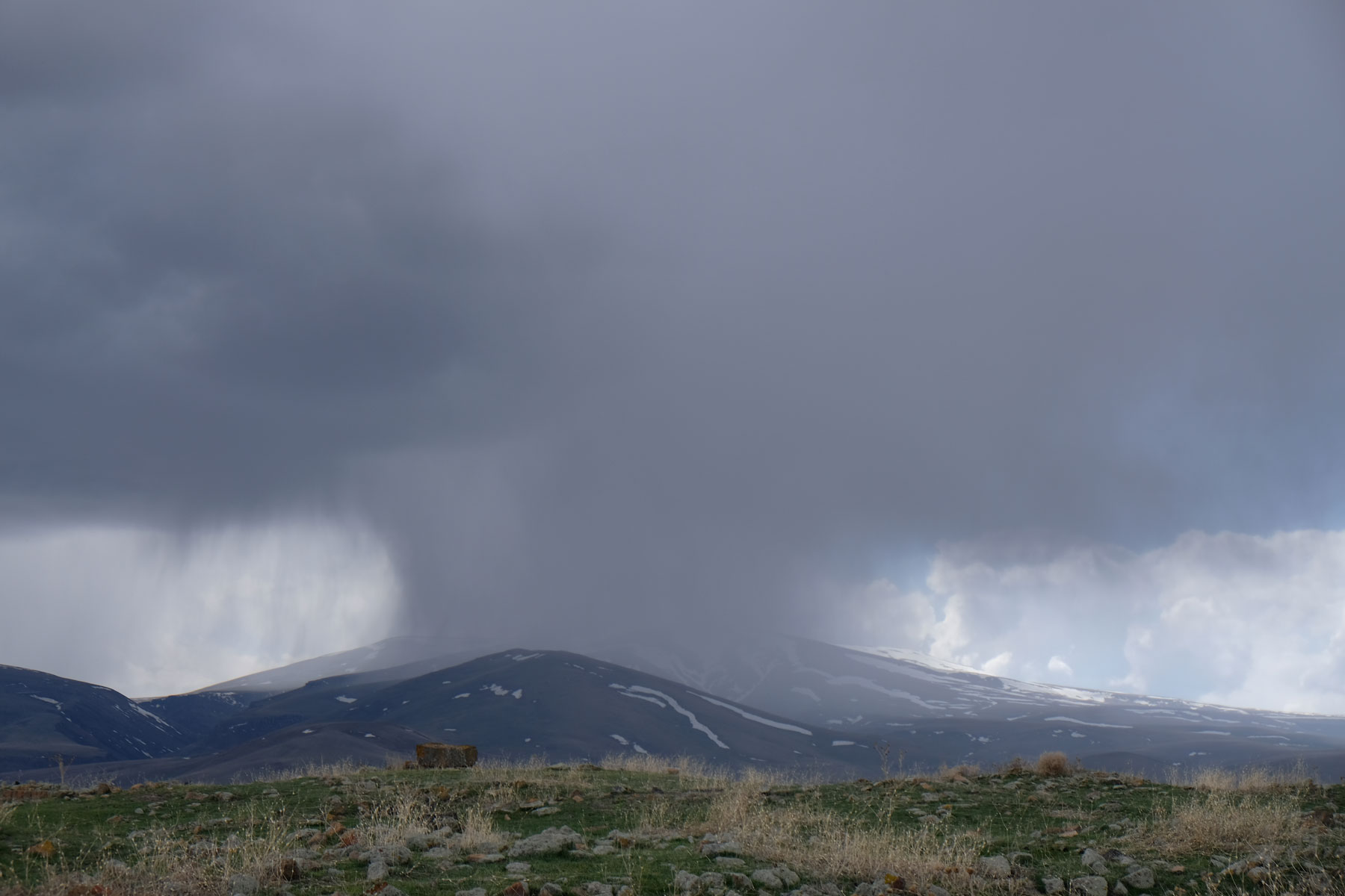 Dunkle Regenwolken und Schauer über einem Berg