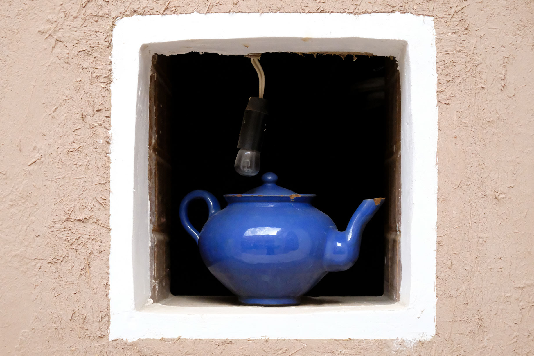 Eine blaue Teekanne in einem kleinen Fenster