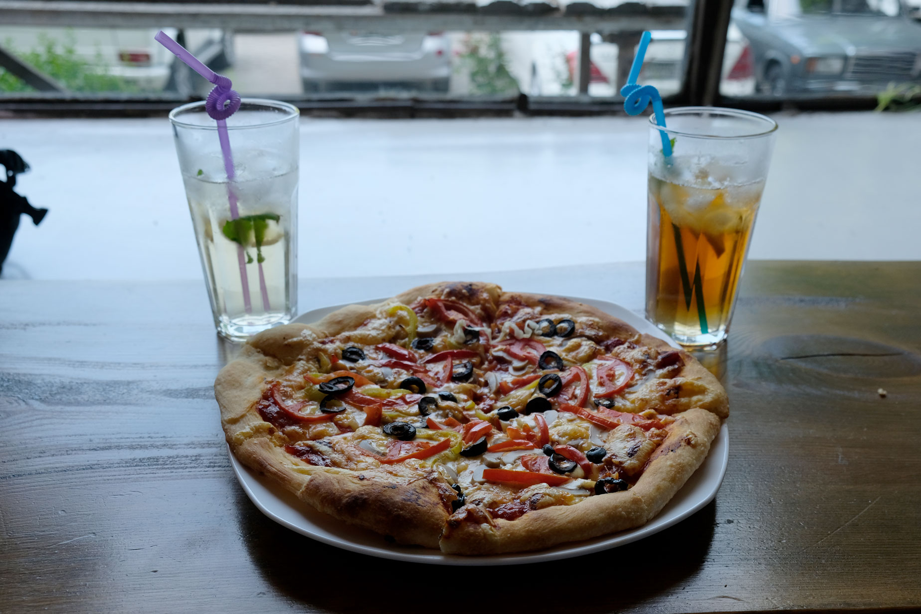 Zwei Getränke neben einer Pizza