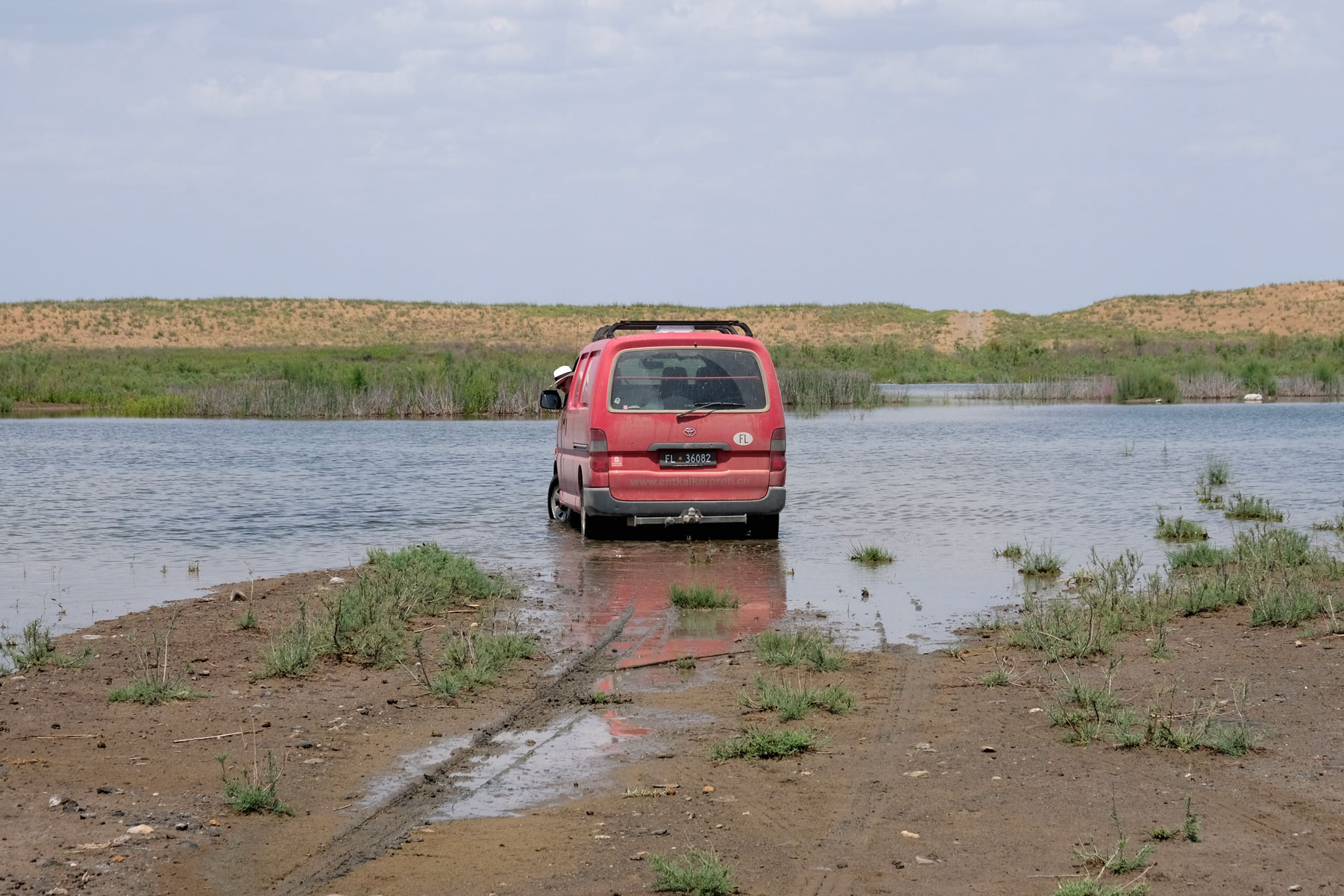 Ein roter Kleintransporter steckt in einem See fest