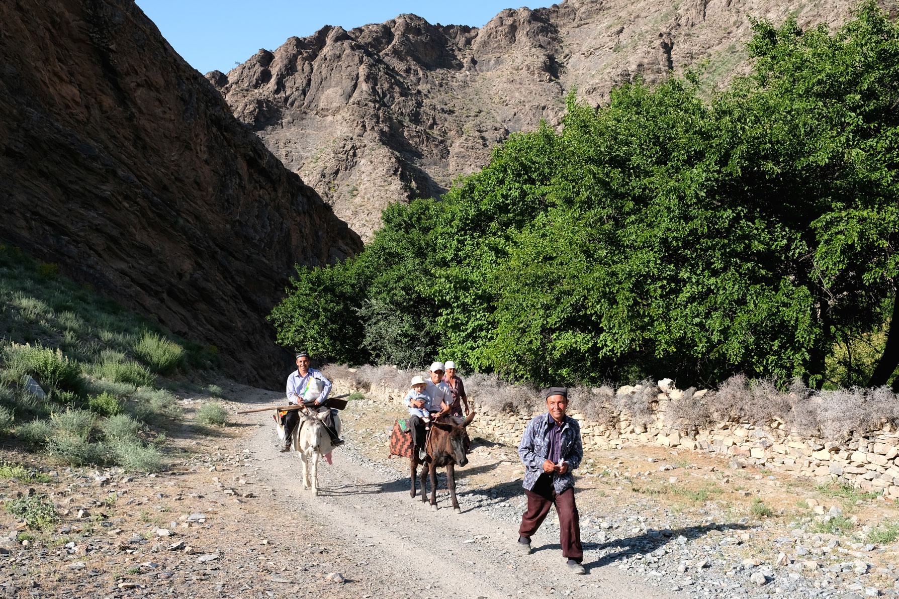 Männer auf Eseln auf einer Schotterstraße im Gebirge