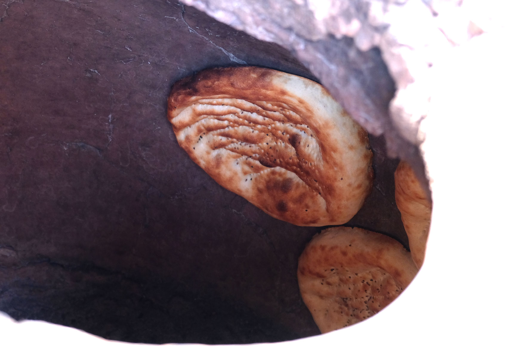 Brotlaibe kleben an der Wand eines Steinofens