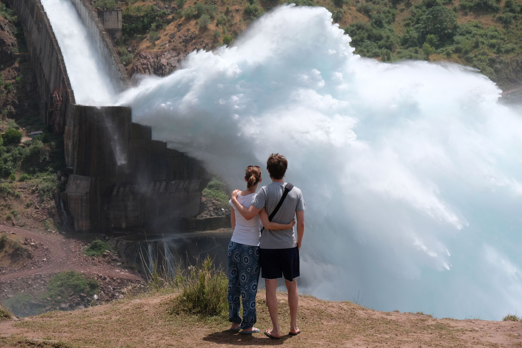 Leo und Sebastian vor einer gigantischen Wasserfontaine am Nurek-Stausee.