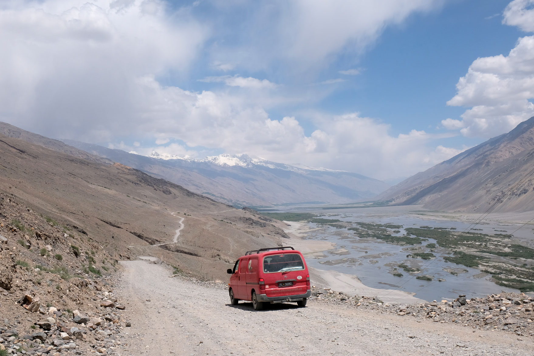 Ein roter Kleintransporter auf einer Schotterstraße auf dem Pamir Highway.