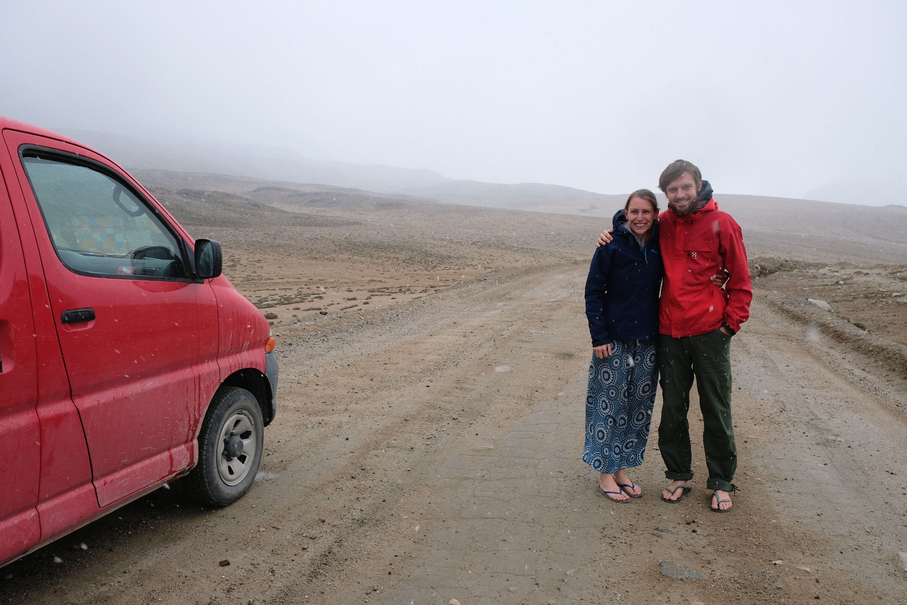 Leo und Sebastian stehen im Nebel neben einem roten Kleintransporter auf dem Kargush-Pass.