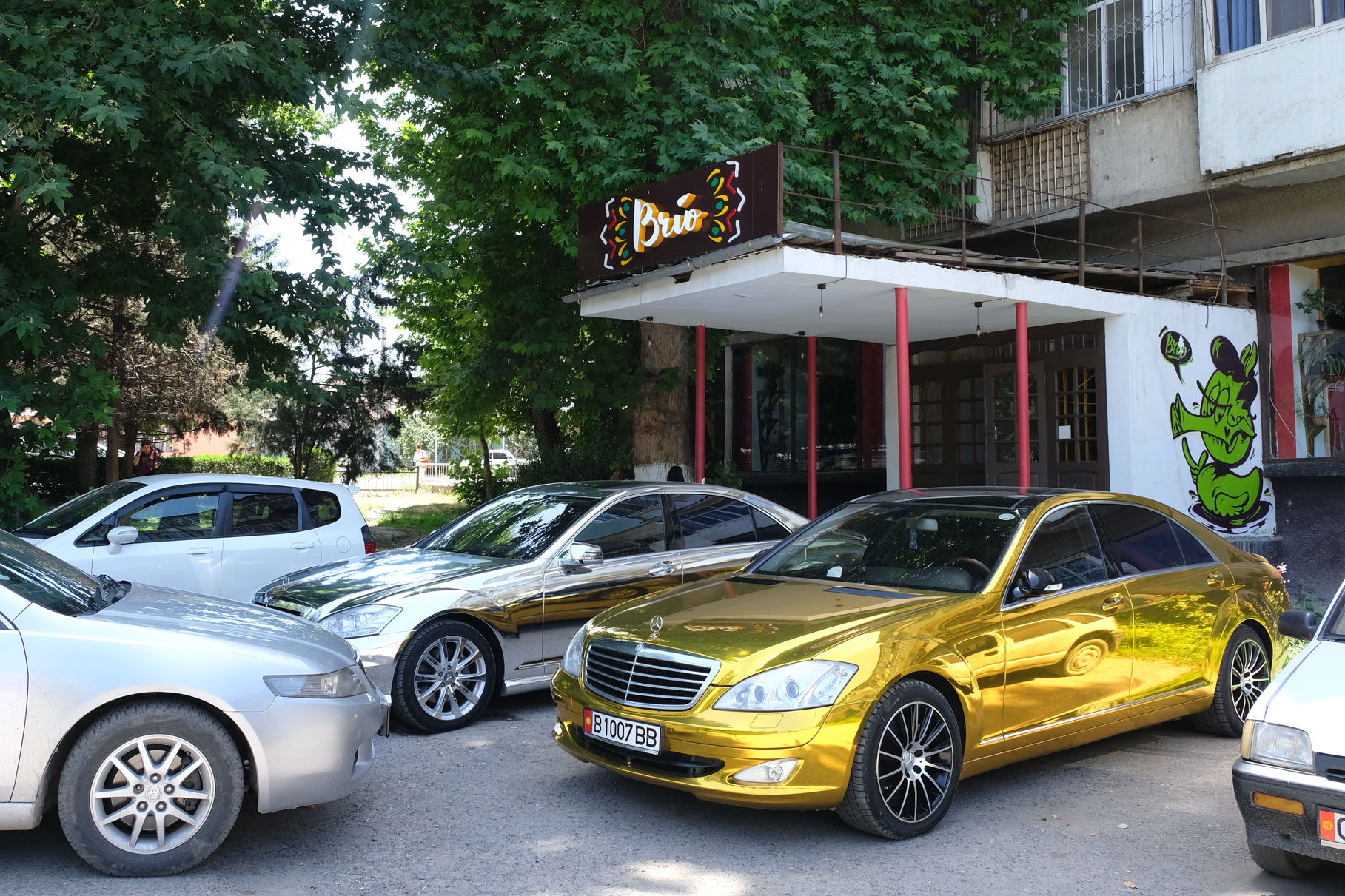 Ein auffällig goldener Mercedes parkt vor dem Brio Café in Osch.