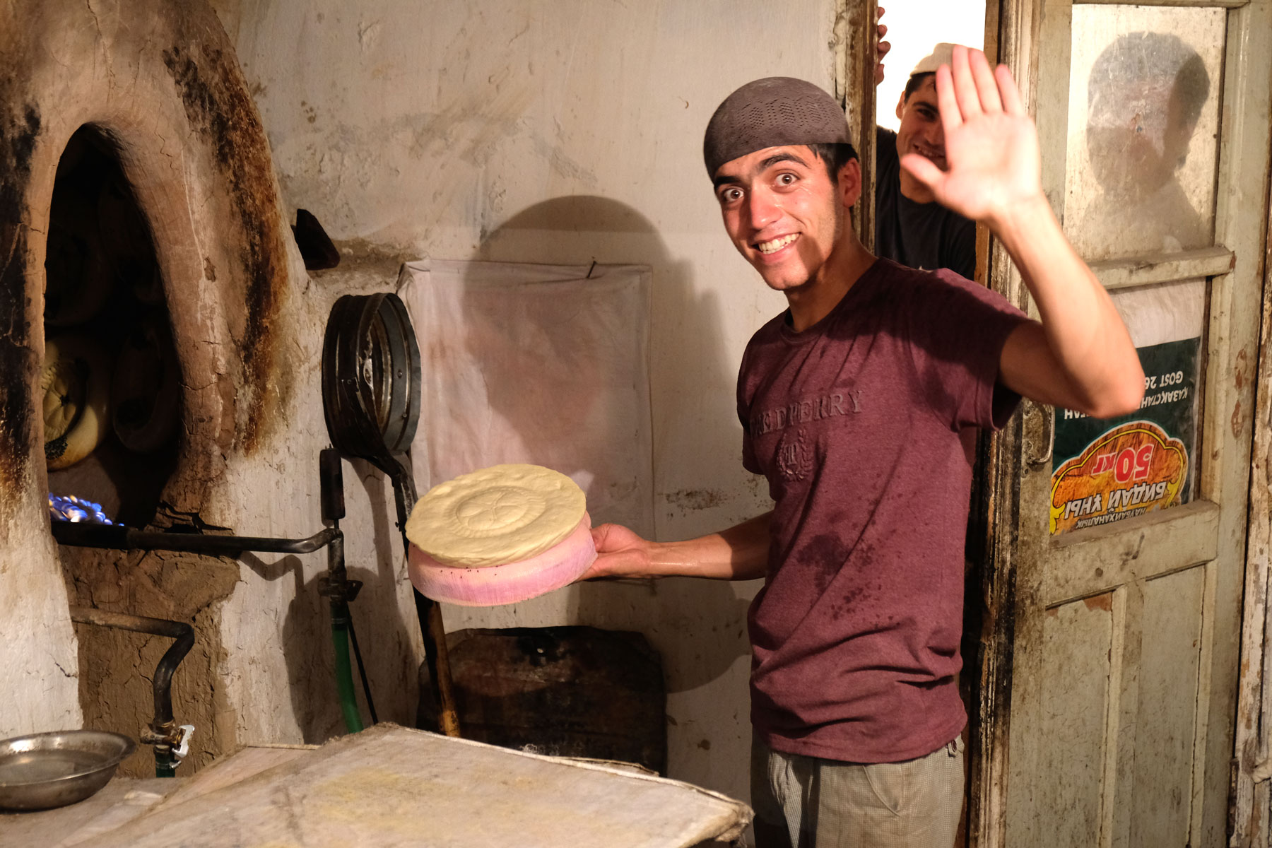 Ein junger Mann hält ein ungebackenes Brot in der Hand.