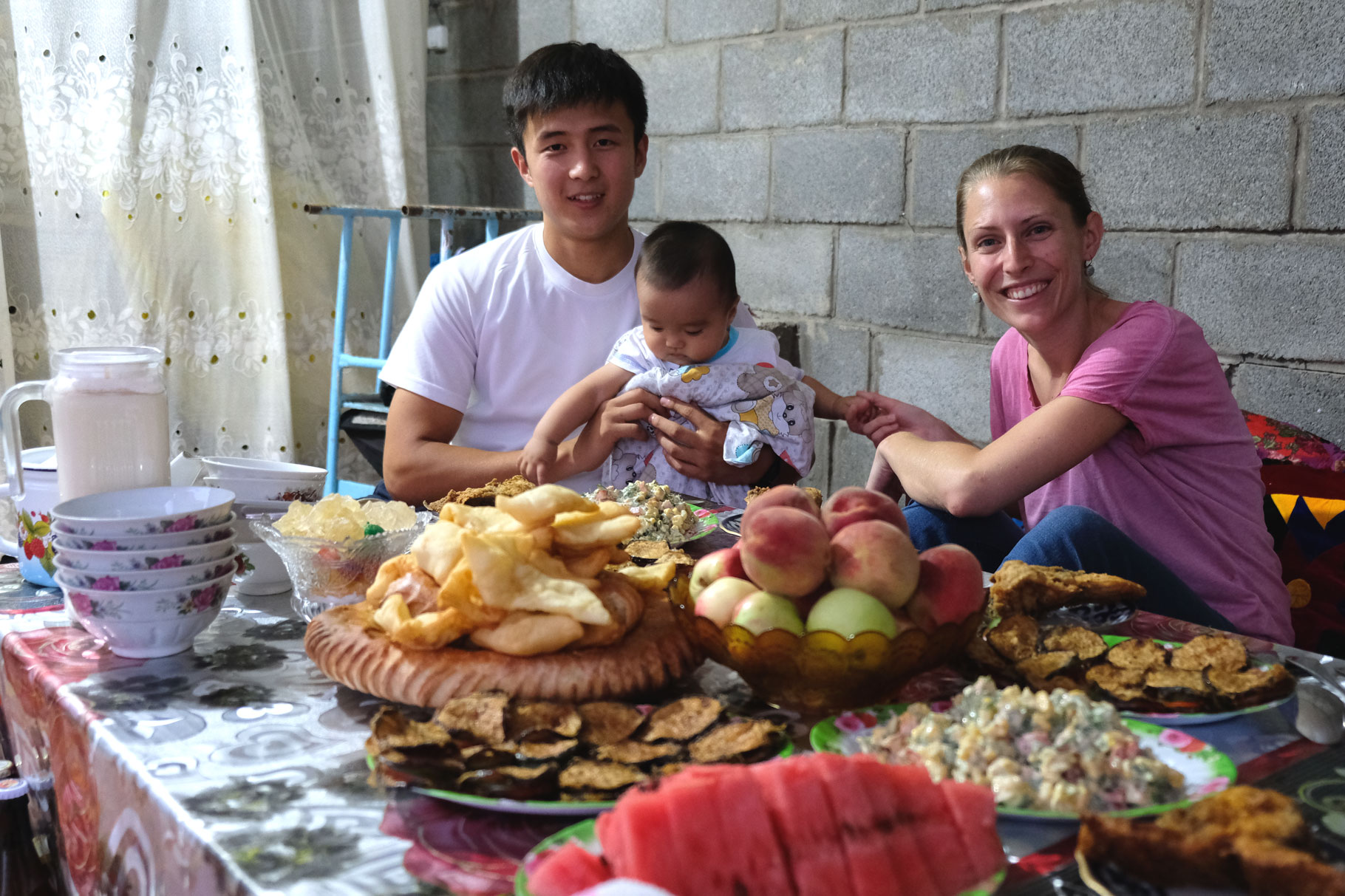 Leo mit Zhumabai und einem Kleinkind an einem Tisch mit Essen.