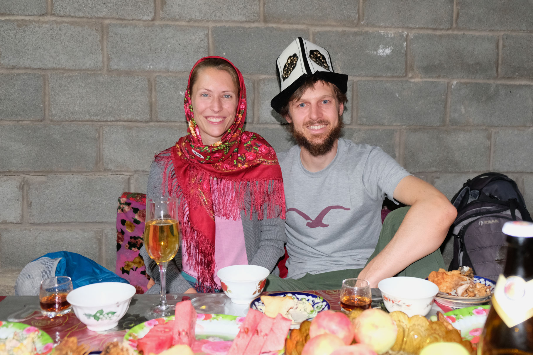 Leo mit Kopftuch und Sebastian mit traditionellem Kalpak sitzen an einem gedeckten Tisch.