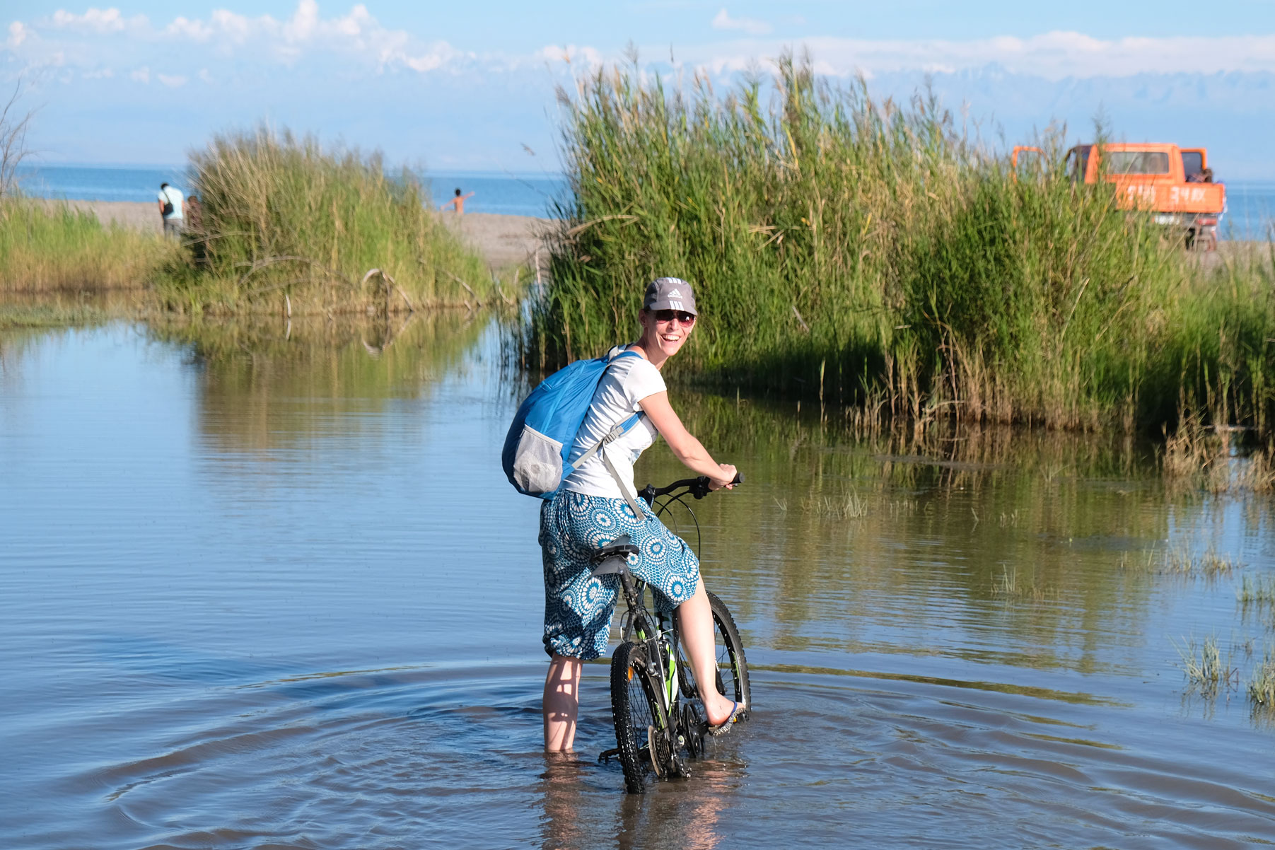 Leo steht mit einem Fahrrad im Wasser.