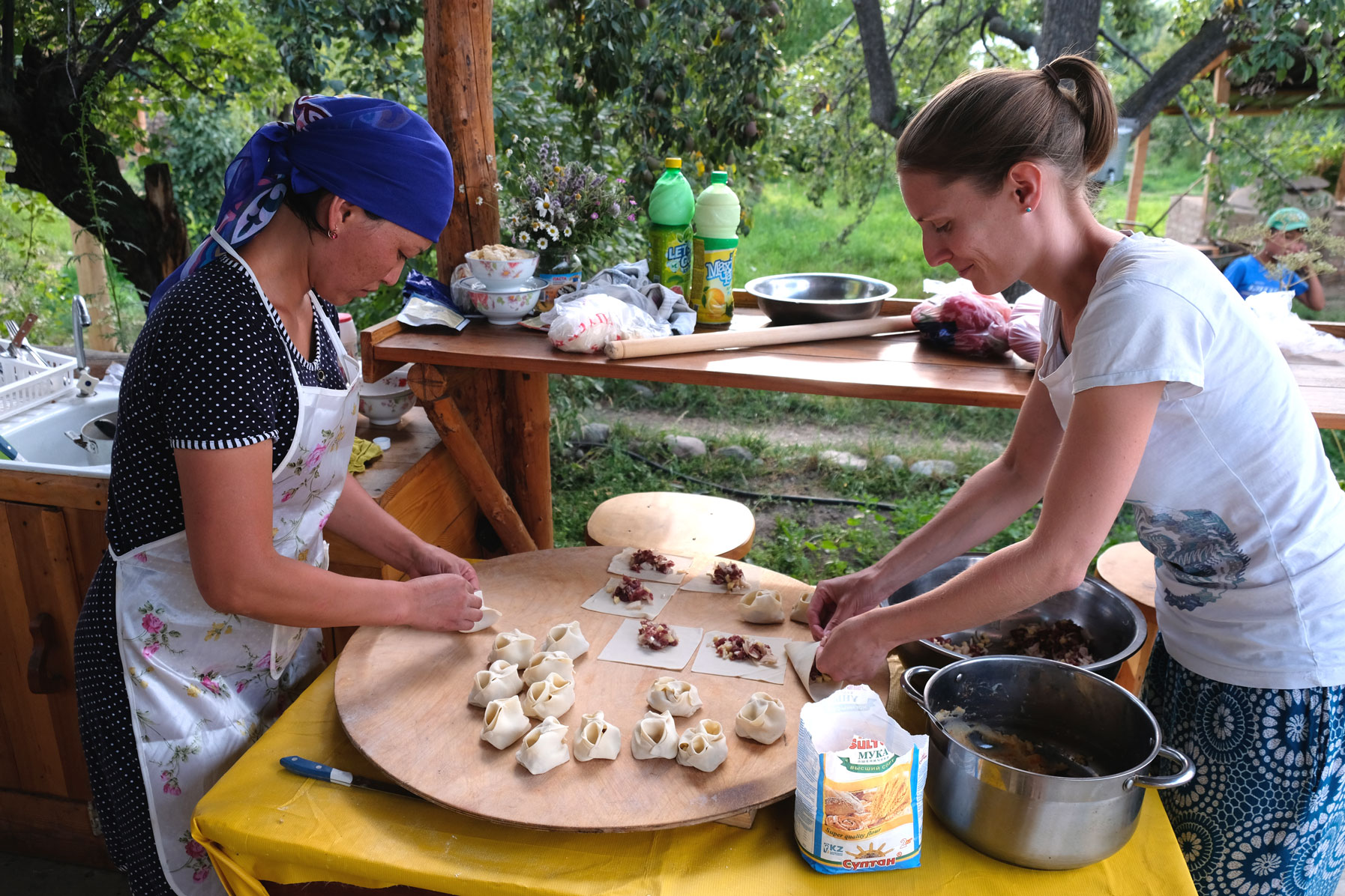 Eine kirgisische Frau und Leo falten Mantı.