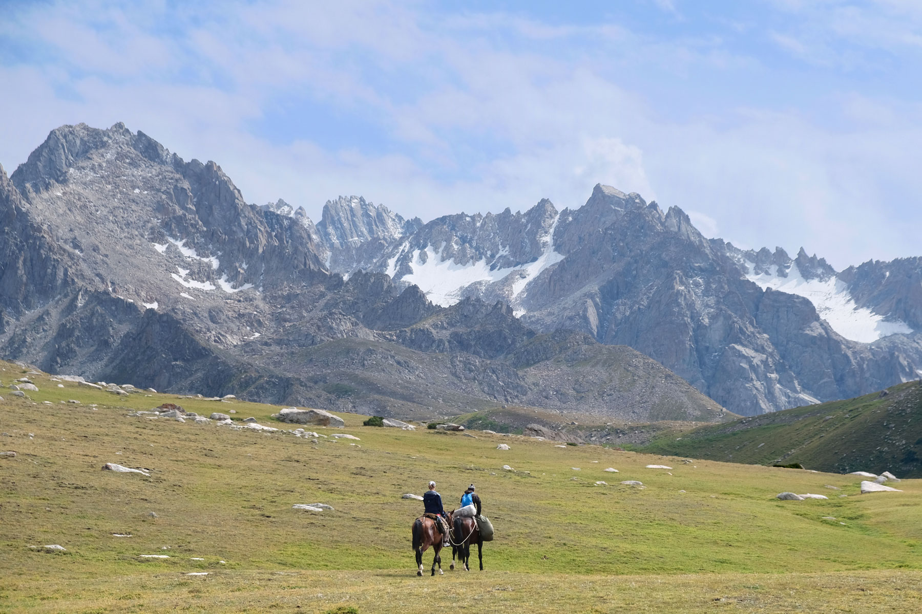 Leos Pferd ist durch ein Seil mit Mikas Pferd verbunden. Sie reiten vor schroffen Bergen.