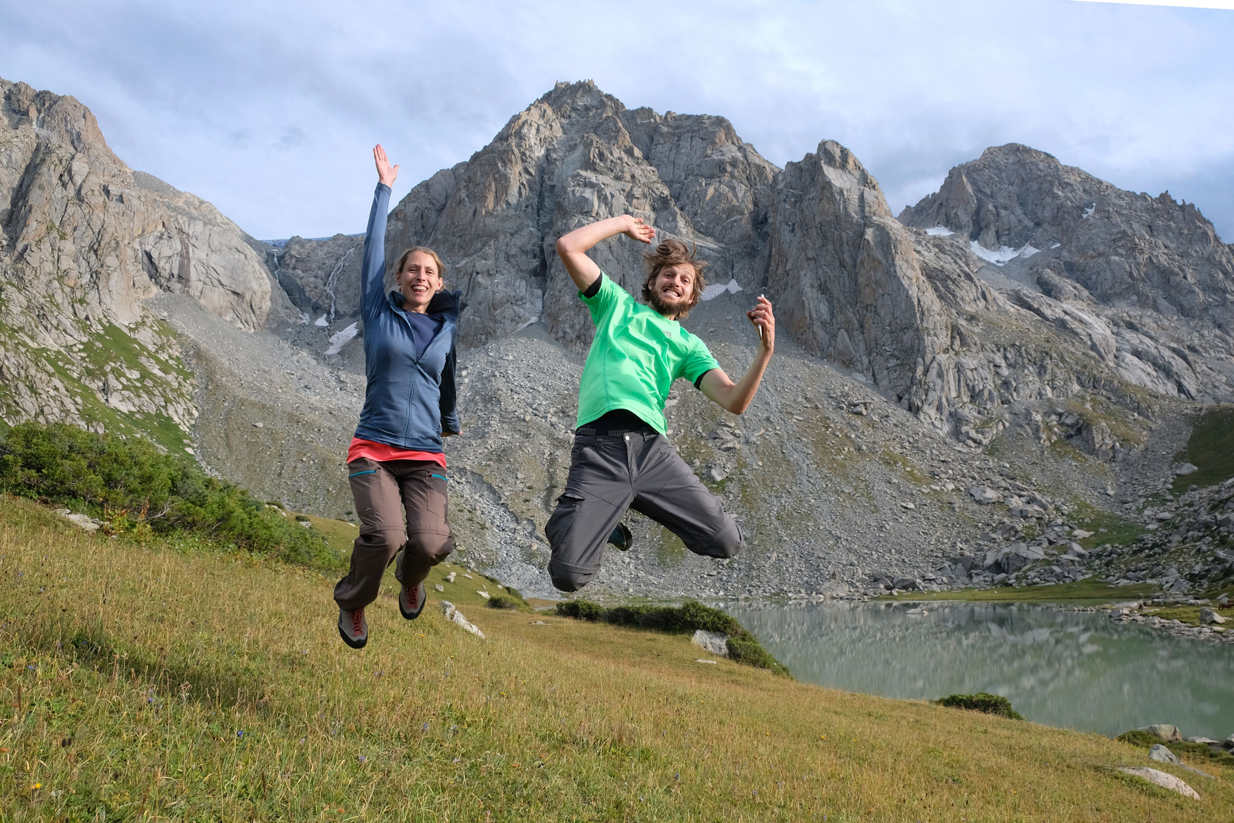 Leo und Sebastian springen vor einem Berg in die Luft.