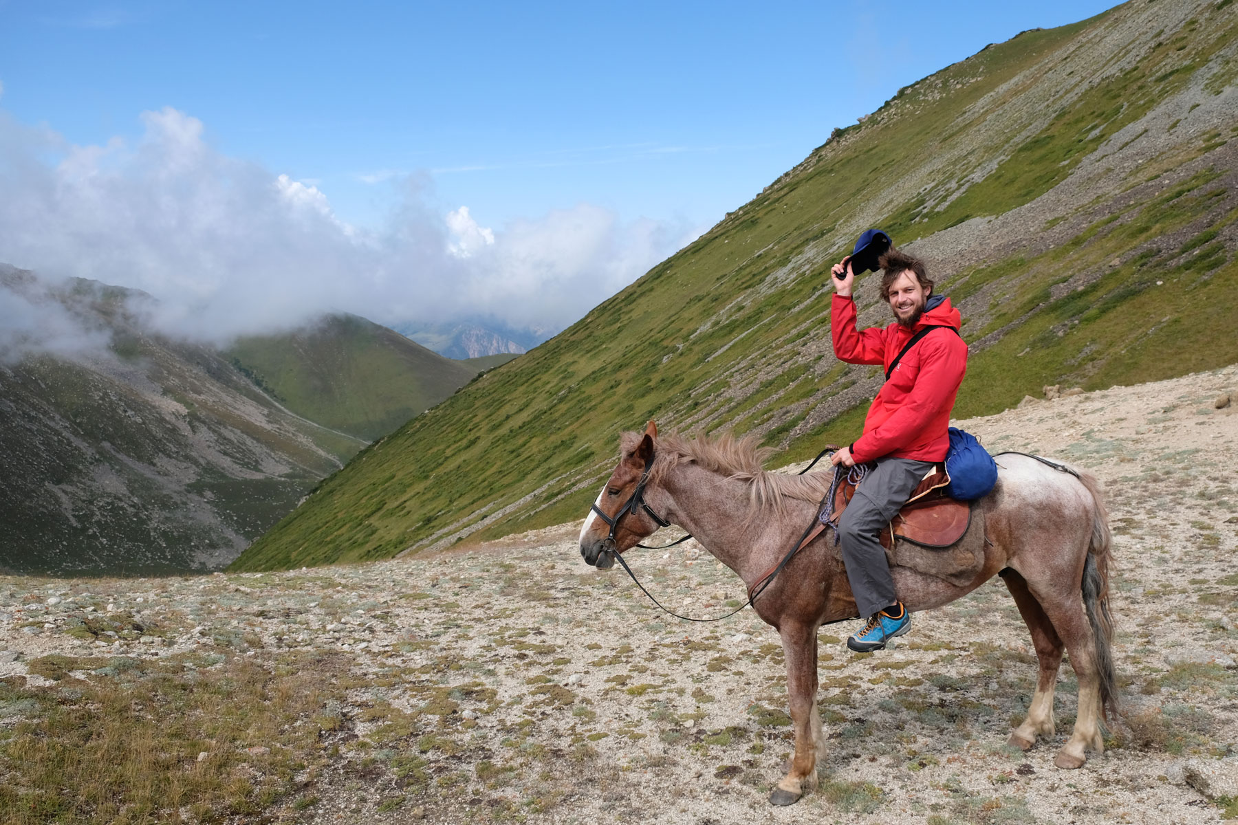 Sebastian sitzt auf einem Pferd und grüßt mit seiner Schildmütze.