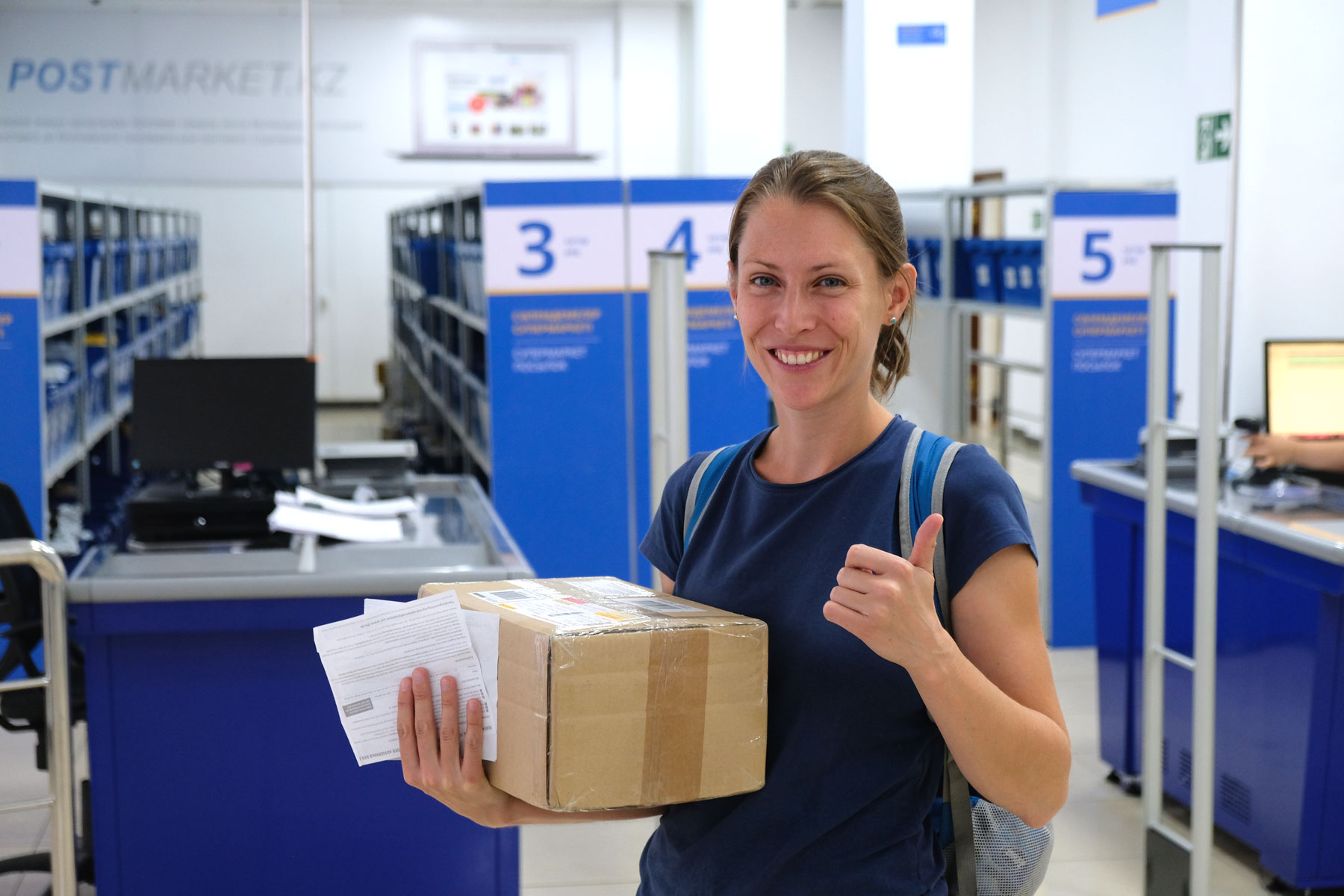 Leo hält im Postamt von Almaty ein Paket in der Hand.