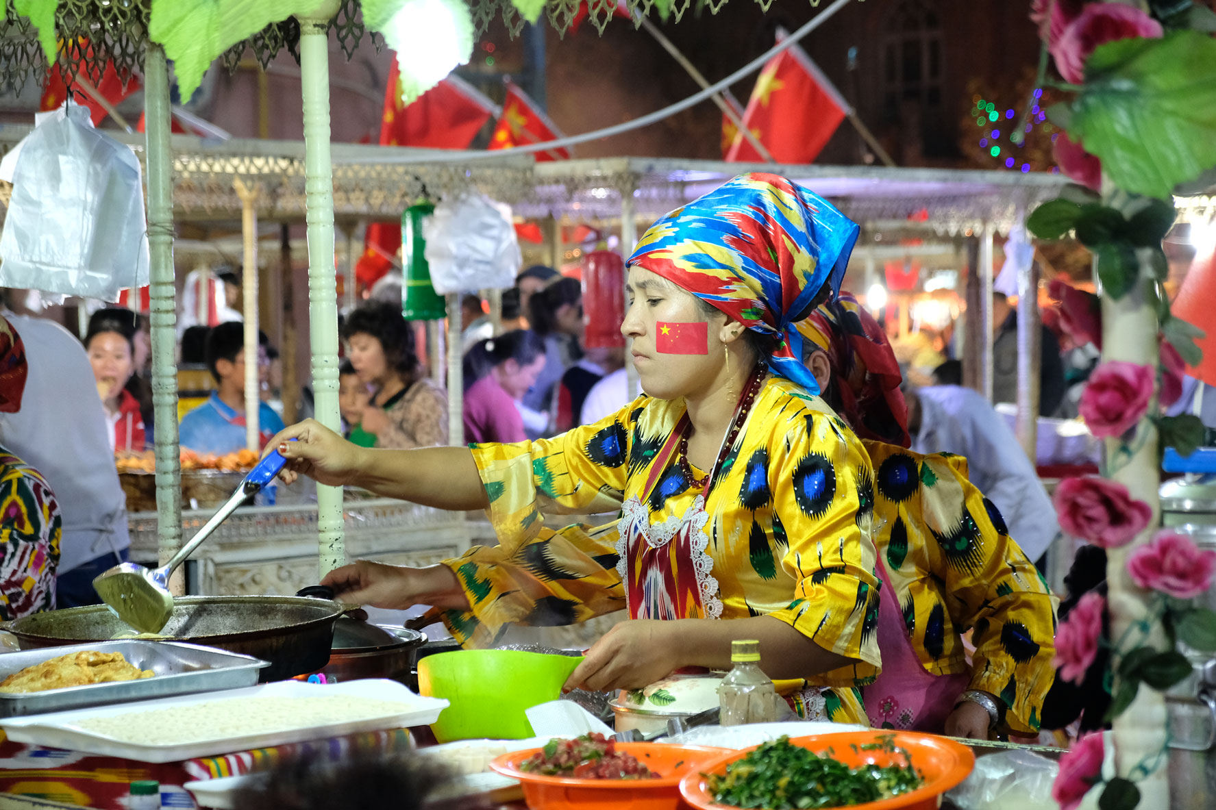 Eine chinesische Frau an einem Essensstand auf dem Nachtmarkt von Kaschgar.