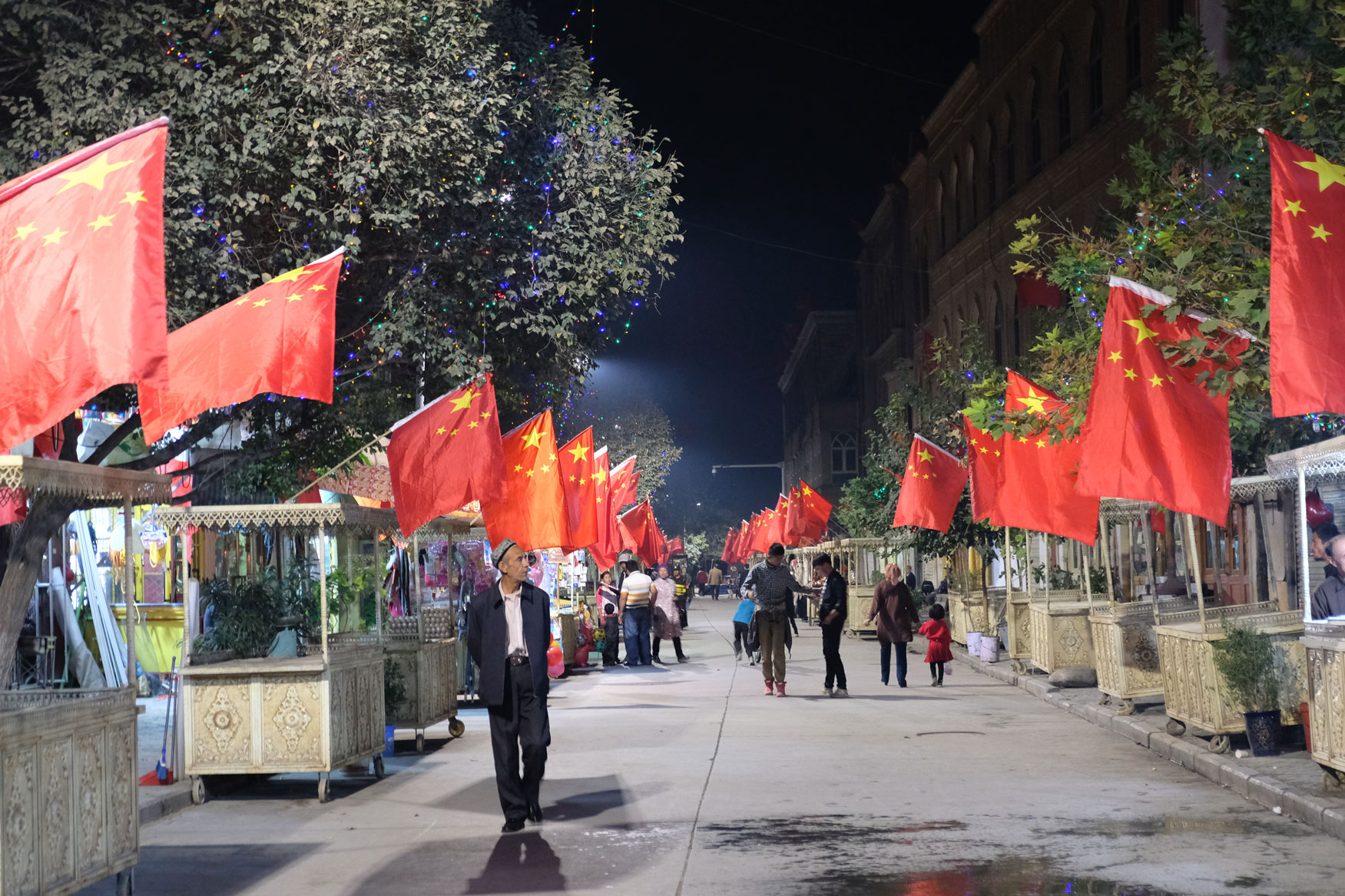 Nachtmarkt in Kaschgar. Die Stände sind mit chinesischen Fahnen geschmückt.
