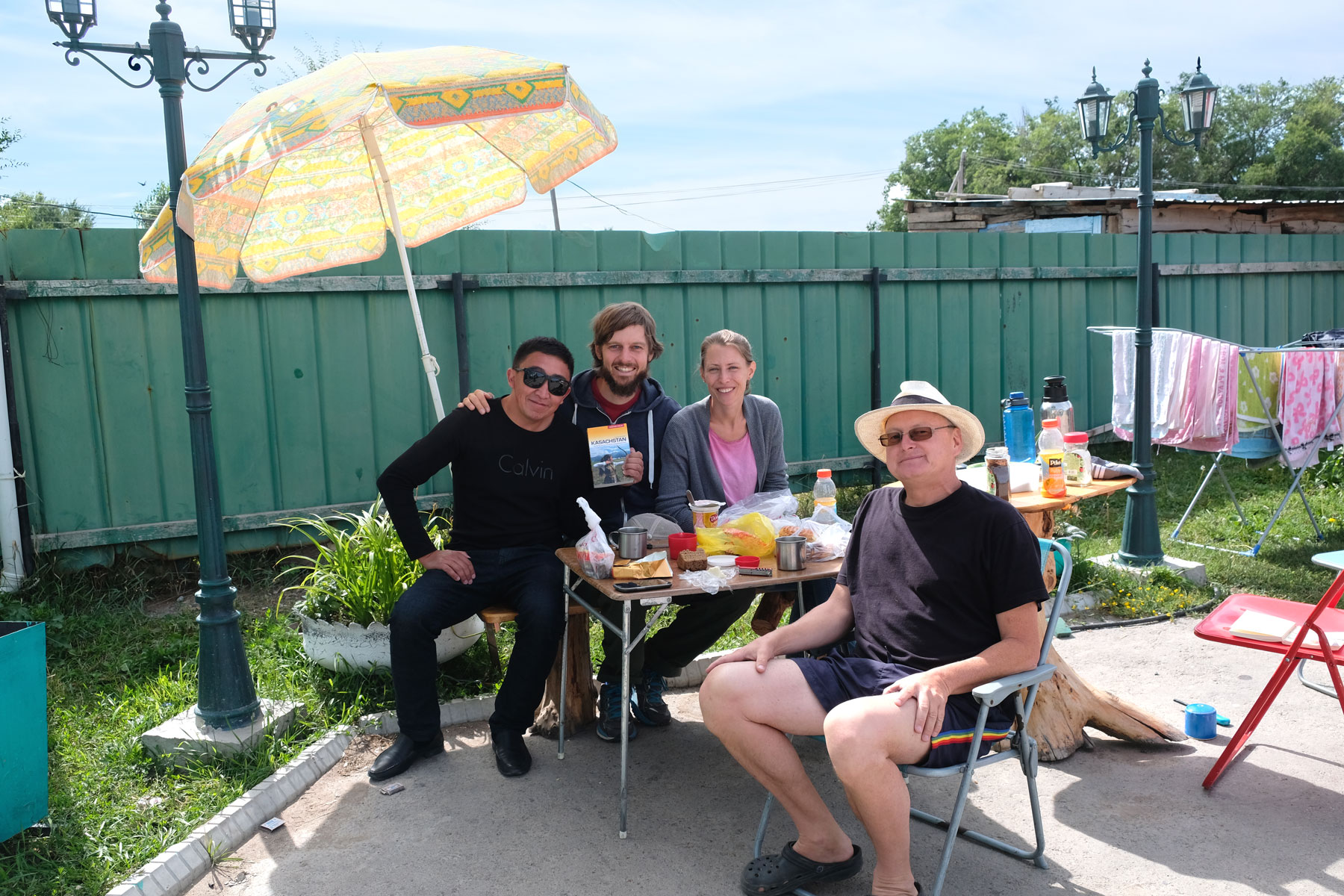 Sebastian und Leo sitzen mit Thomas und einem Kasachen beim Frühstück im Freien.