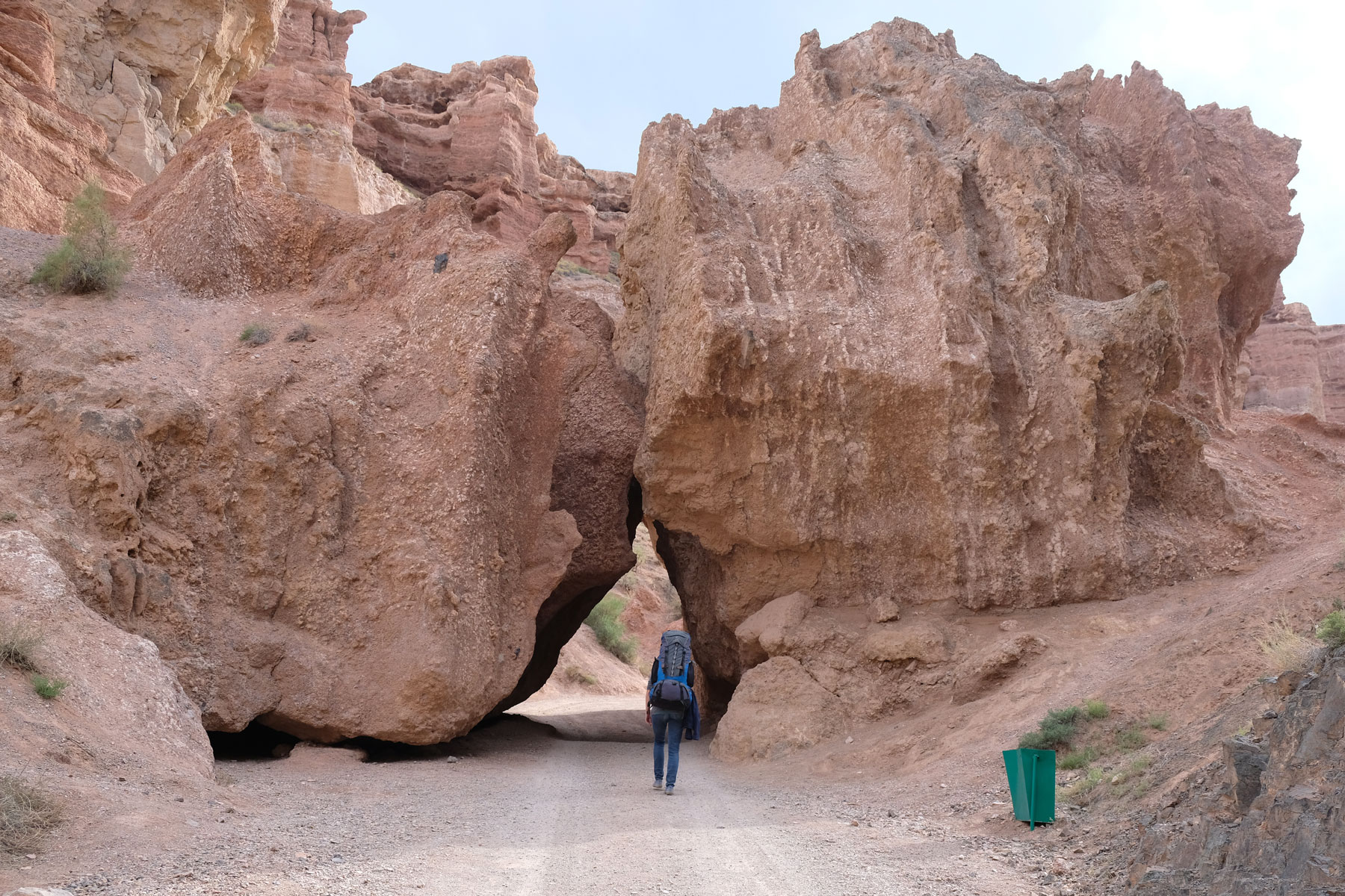 Leo läuft mit Rucksack auf dem Rücken durch eine Felsöffnung im Charyn Canyon