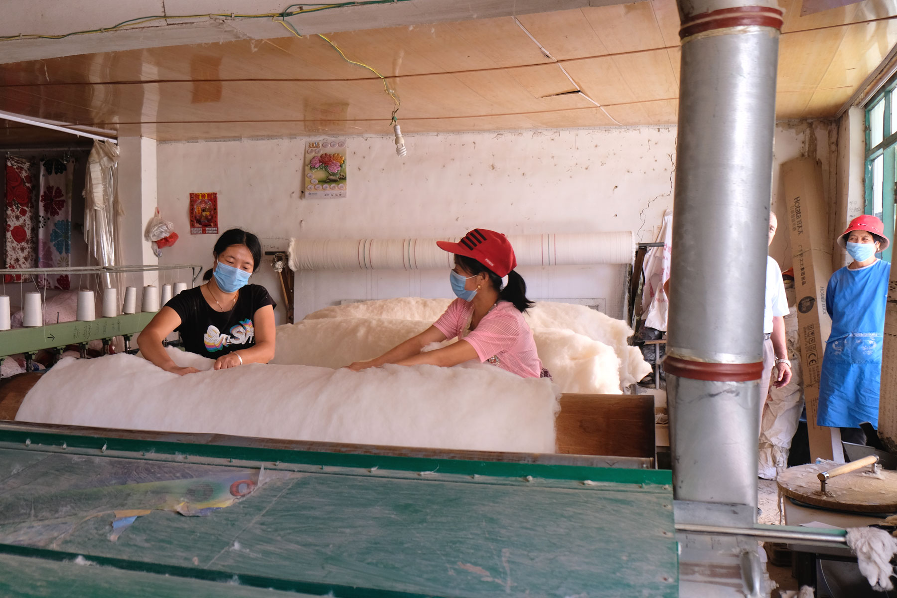 Zwei Frauen verarbeiten Baumwolle an einer Maschine in Hotan.