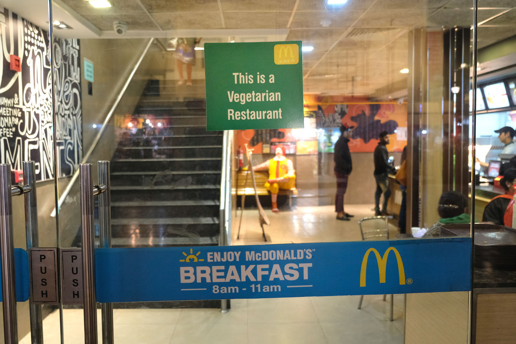 Eingangstür zu einer McDonald’s Filiale in Amritsar. Ein Schild weist darauf hin, dass dies ein vegetarischer McDonald’s ist.