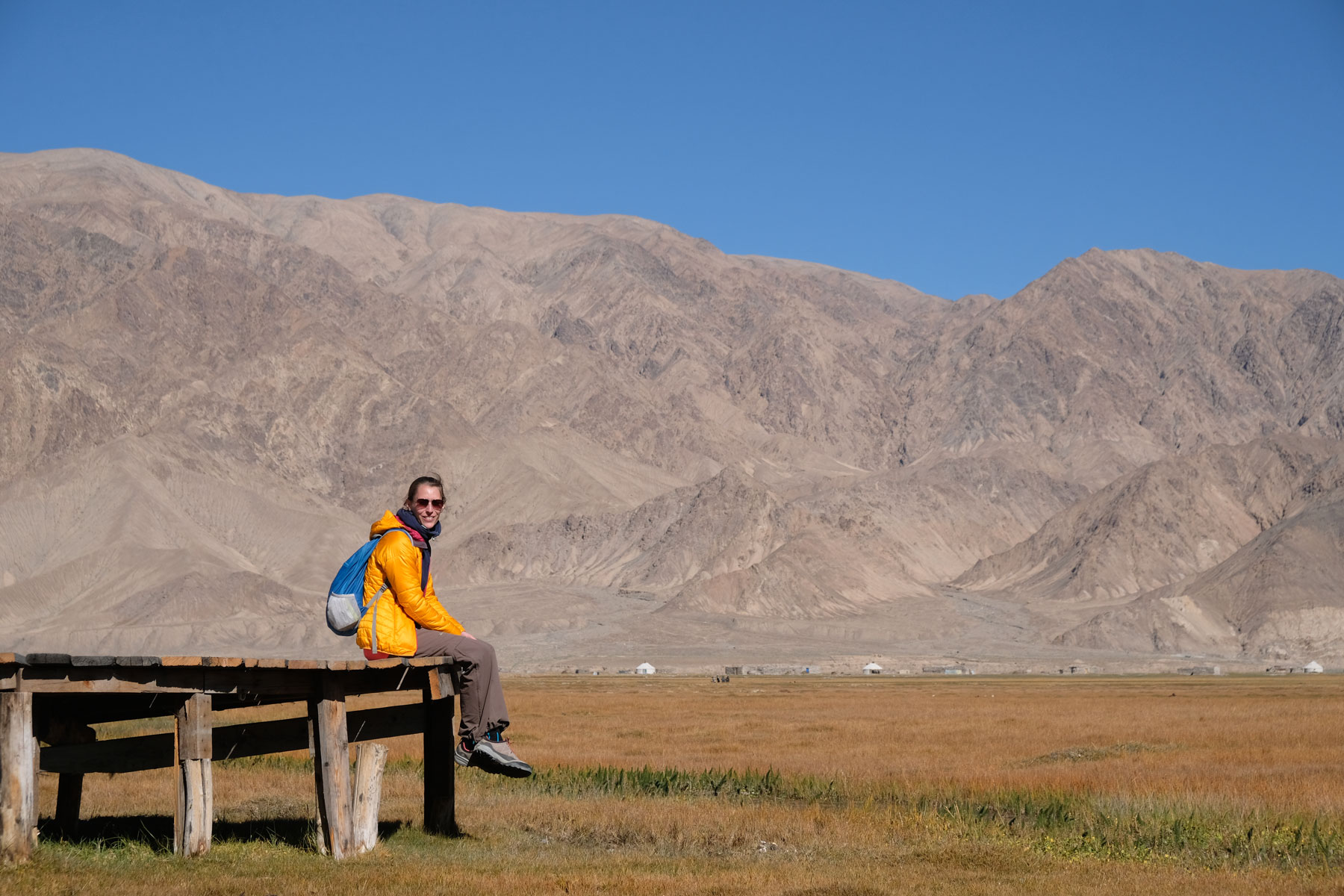 Leo sitzt auf einem Holzsteg in den Grasslands bei Tashkurgan.