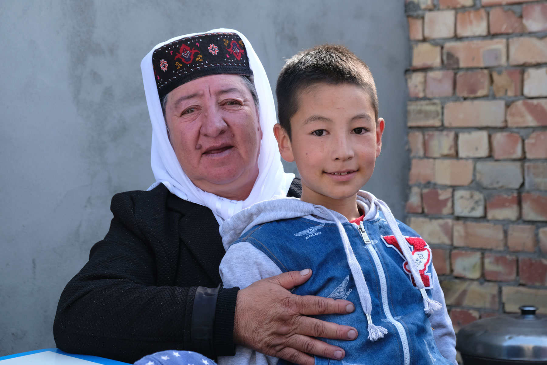 Eine uigurische Frau in Tracht mit einem Jungen.