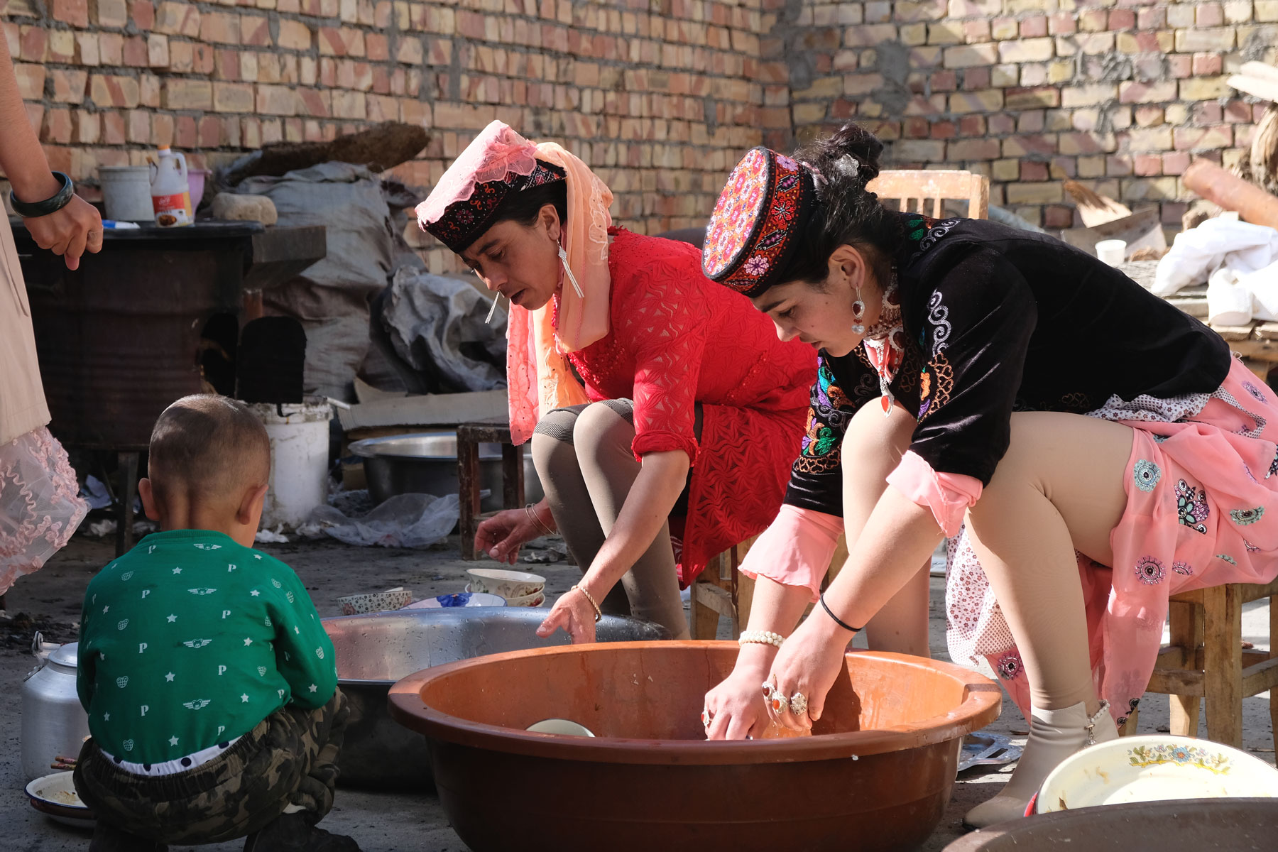 Zwei Frauen waschen in Wannen Geschirr ab.