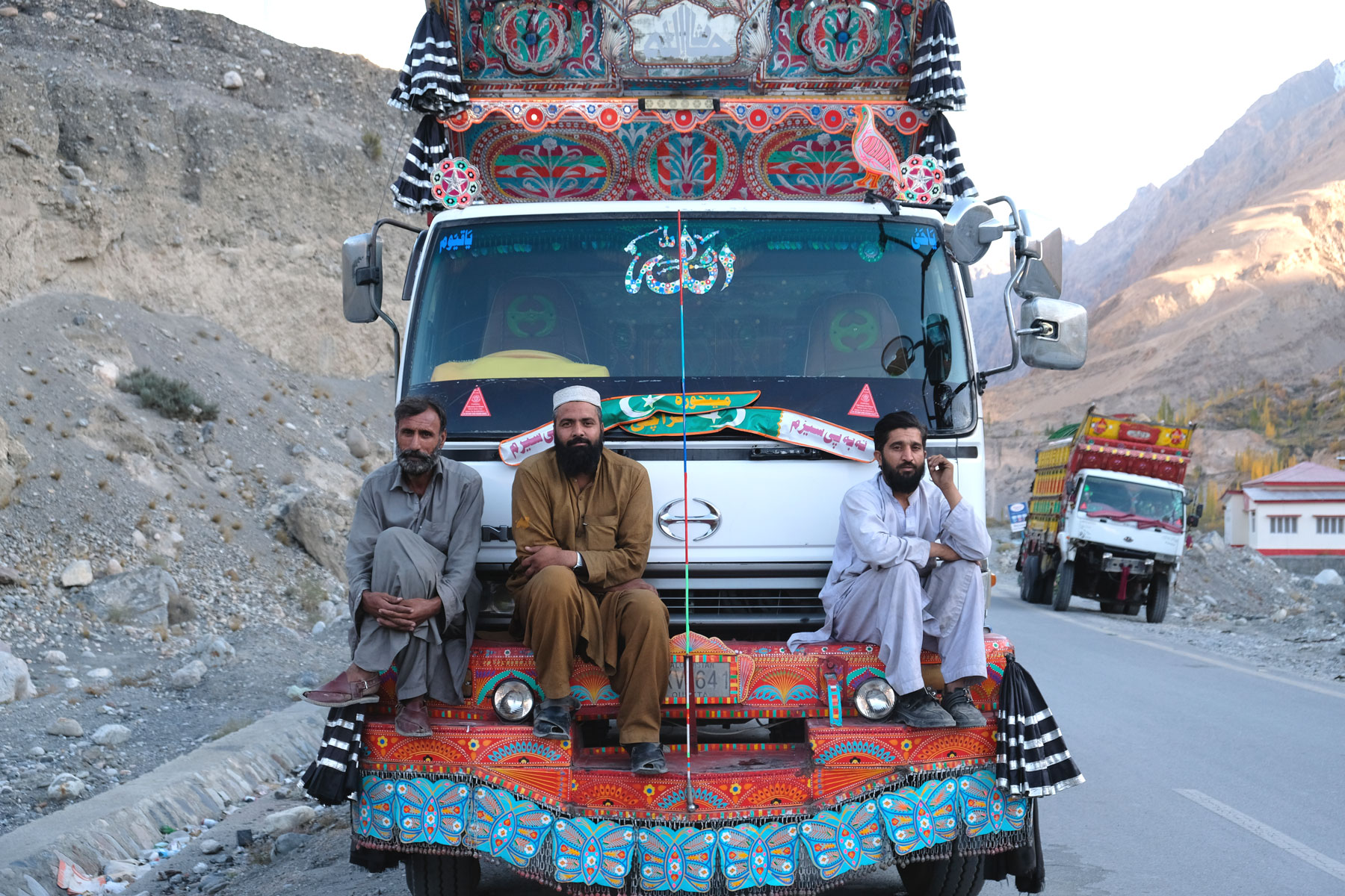 Pakistanische Männer sitzen auf einem verzierten Lastwagen.