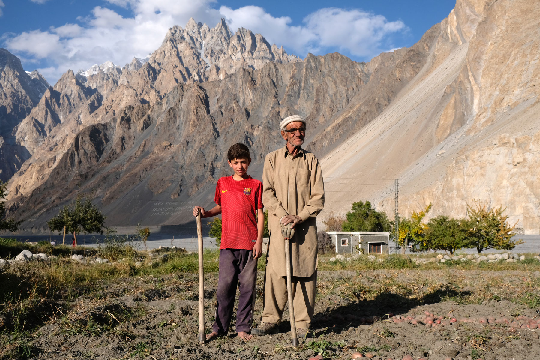 Ein alter Mann steht neben einem Jungen auf einem Feld im Karakorumgebirge.