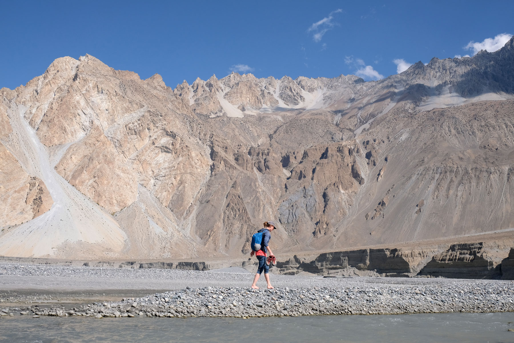 Leo läuft barfuß auf dem steinigen Ufer des Hunza-Flusses.