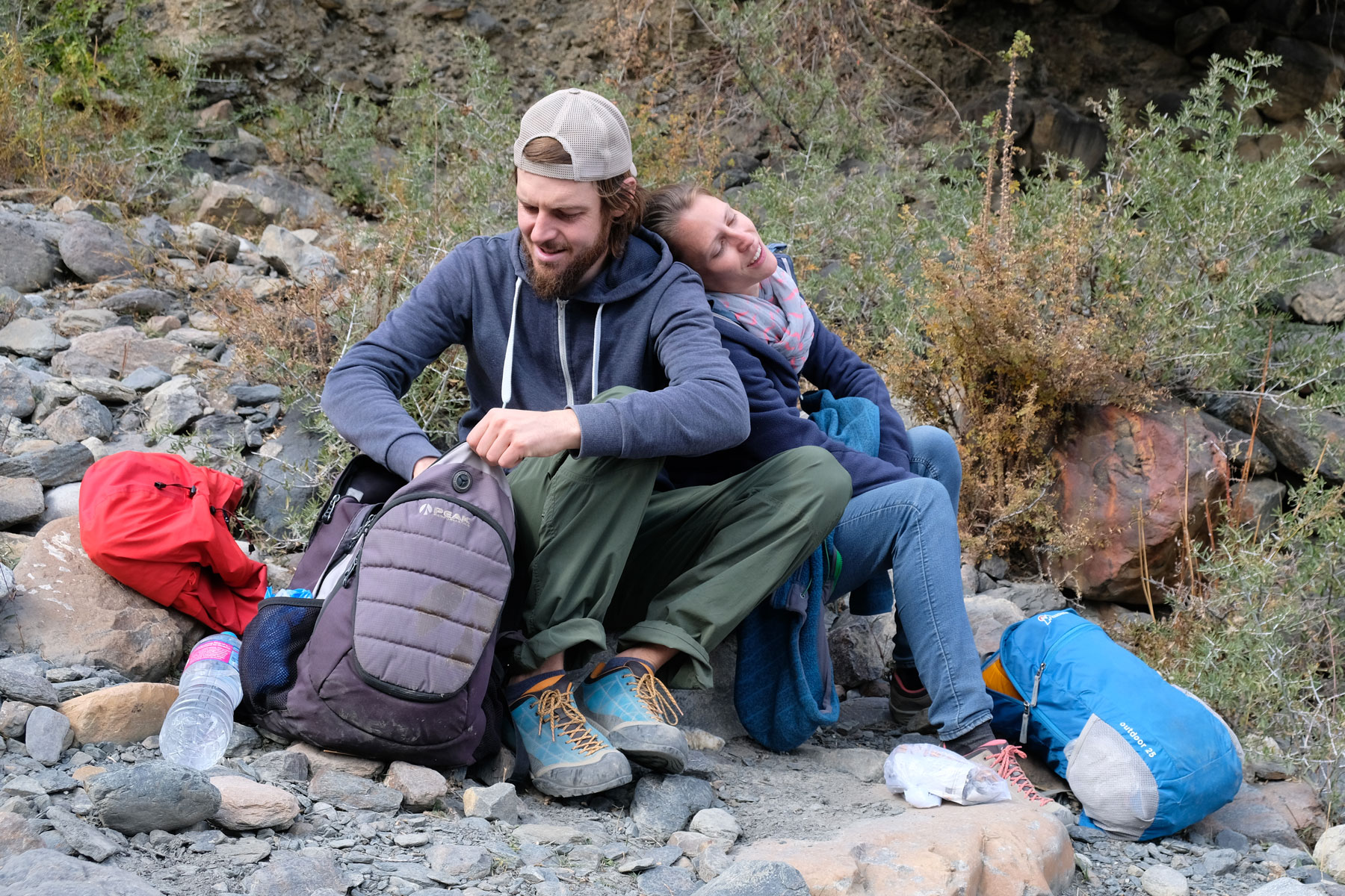 Sebastian und Leo sitzen auf Steinen und hole etwas aus einem Rucksack.