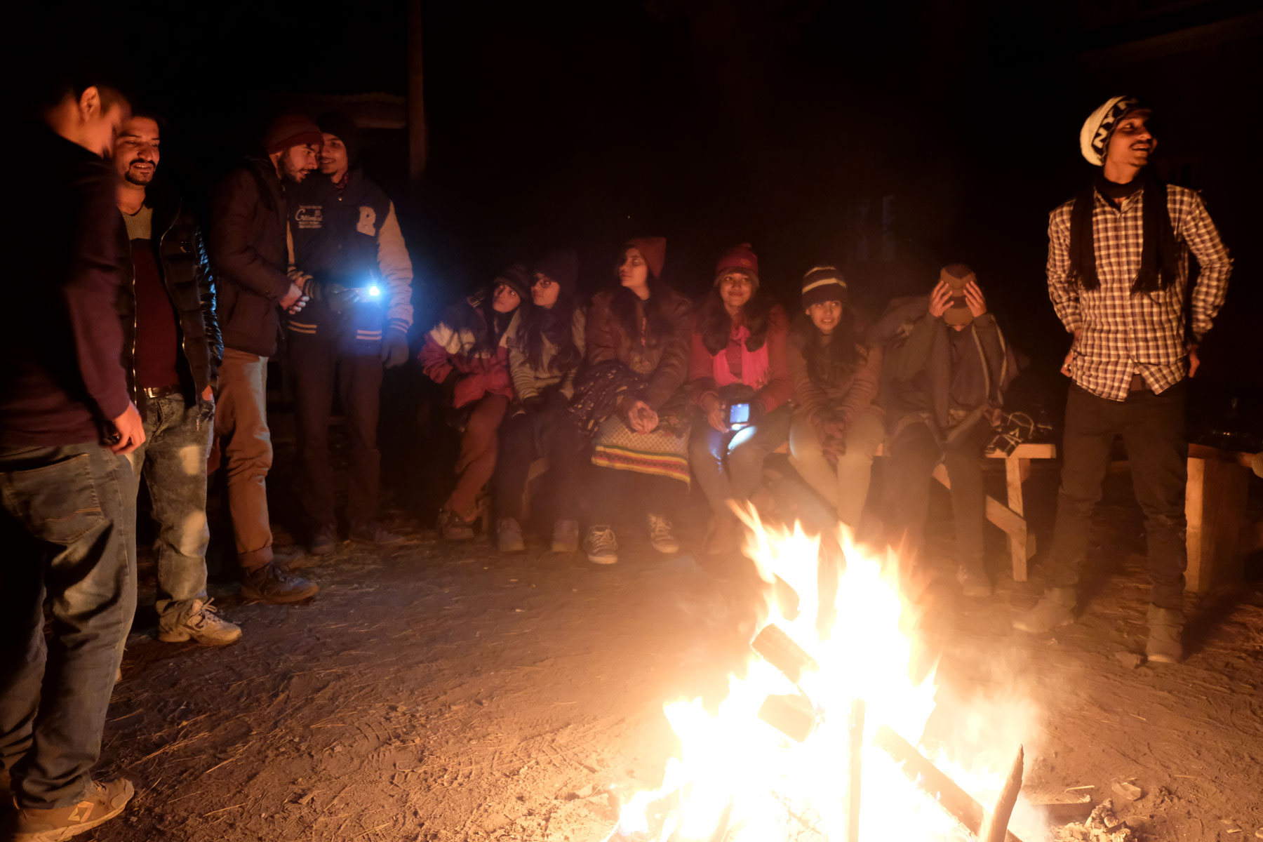 Menschen sitzen und stehen um ein Lagerfeuer in Fairy Meadows.