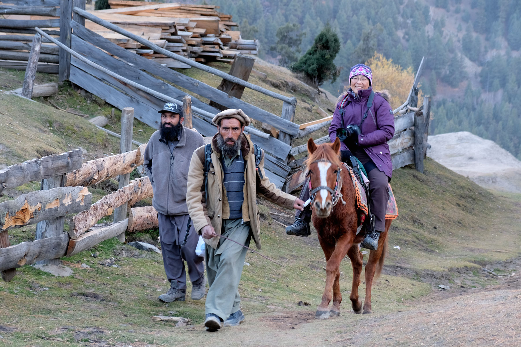 Zwei Männer führen eine Frau, die auf einem Pferd sitzt, nach Fairy Meadows.
